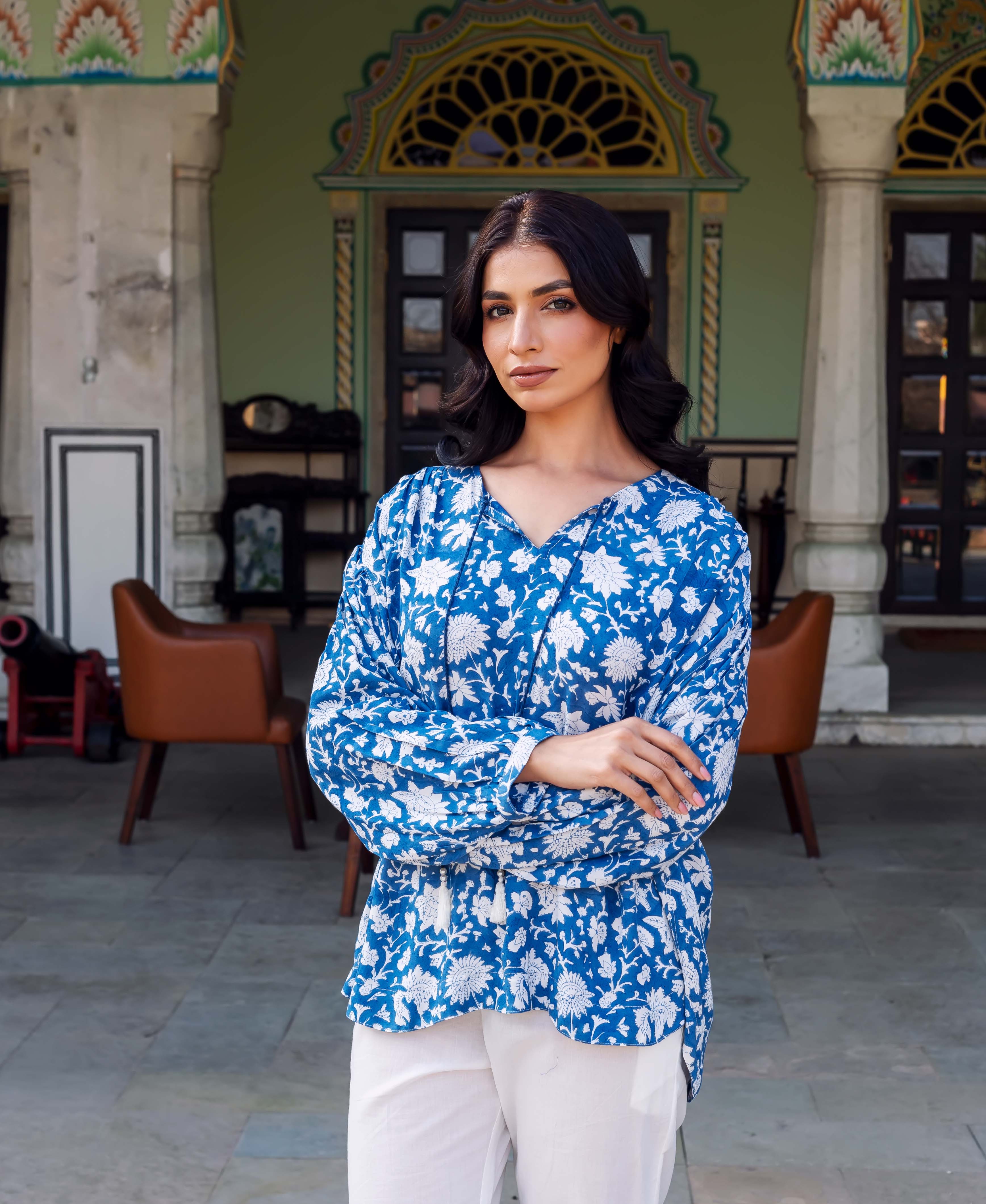Standing model in a vibrant blue hand-printed floral tunic and white pants.
