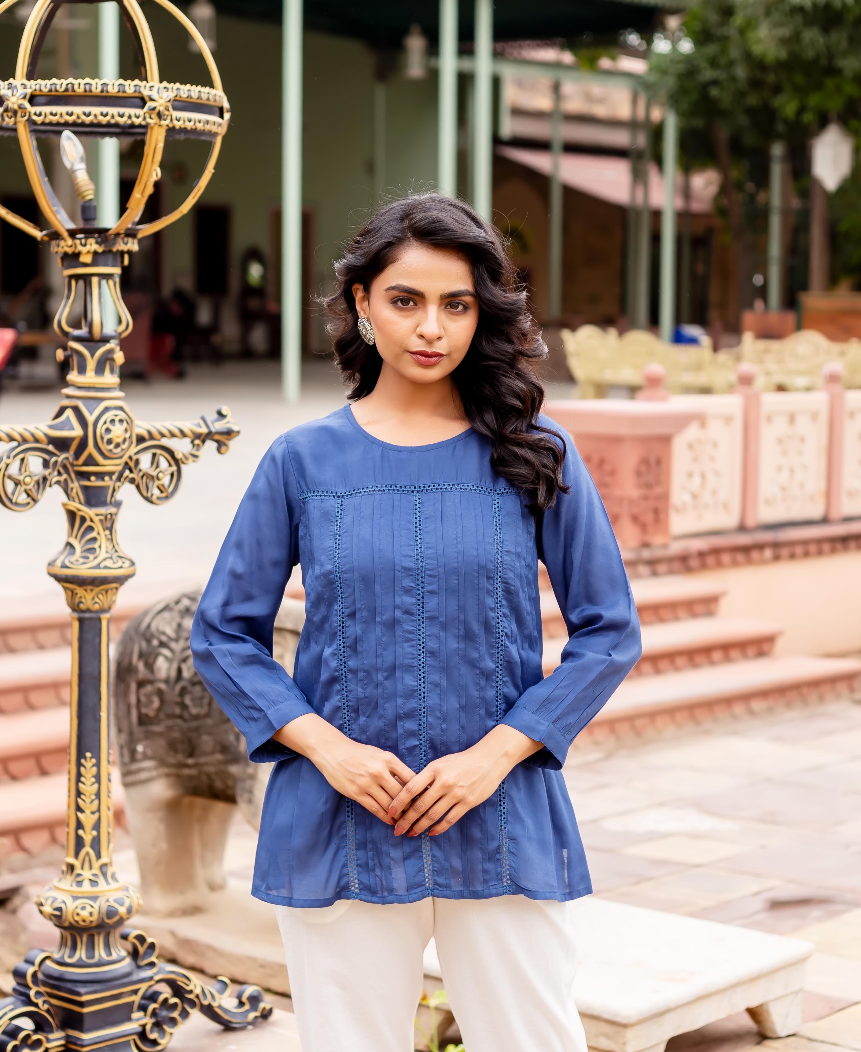 Model wearing a navy blue pleated tunic with lace details and white pants.