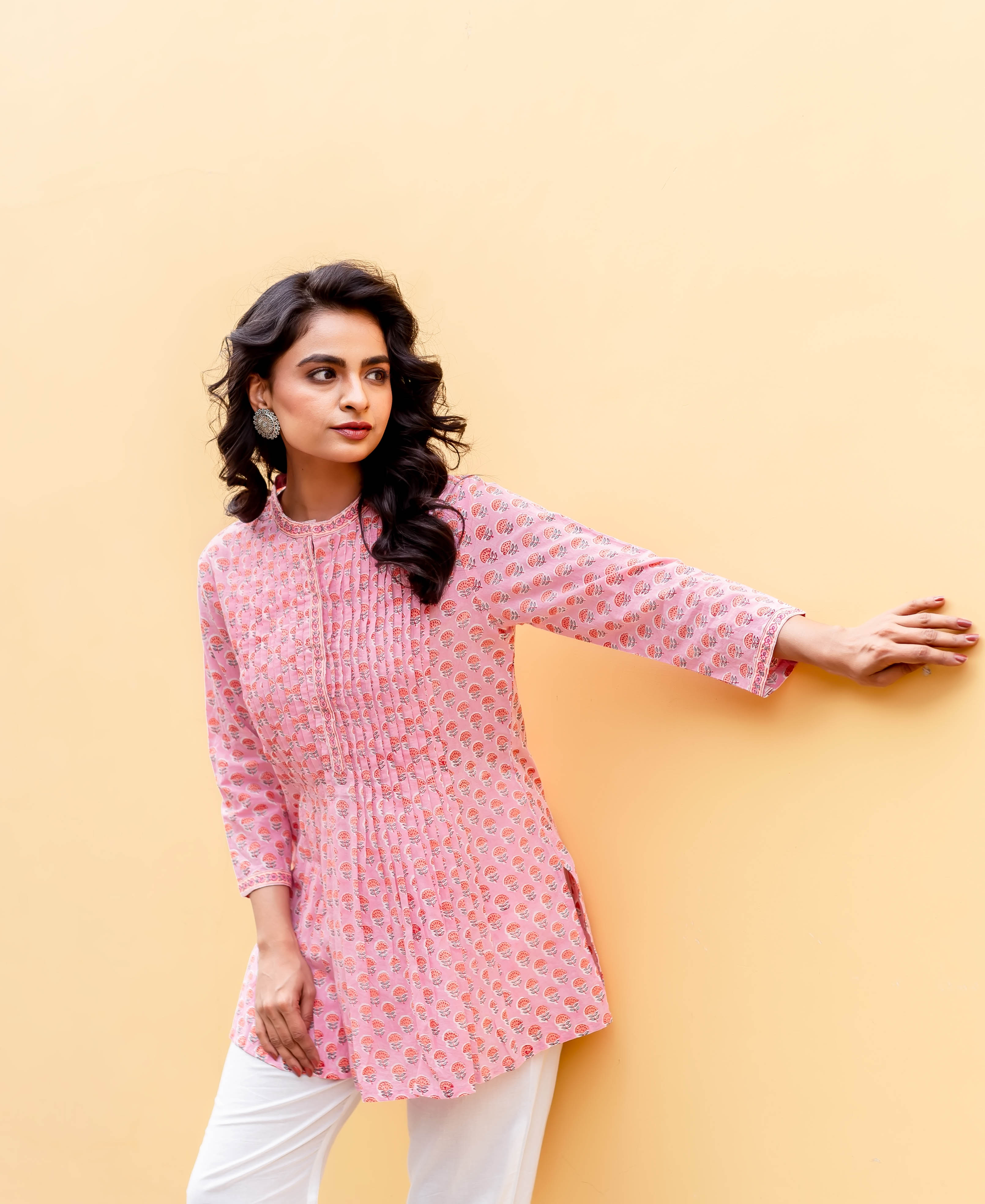 Three-quarter shot of a model wearing a blush pink tunic with pintuck detailing and block print.