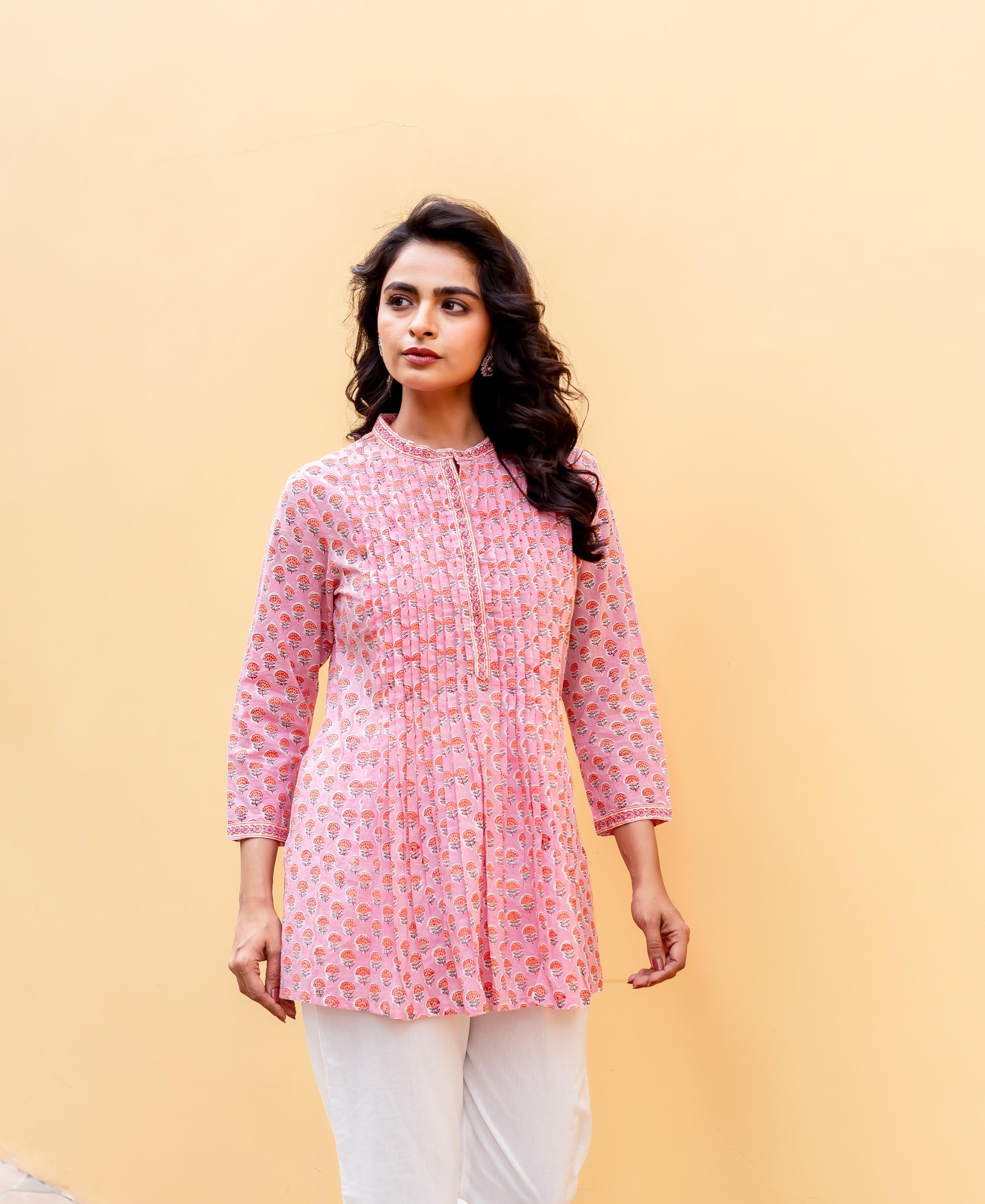 Model wearing blush pink floral hand-block-printed tunic featuring front pintucks and white pants.