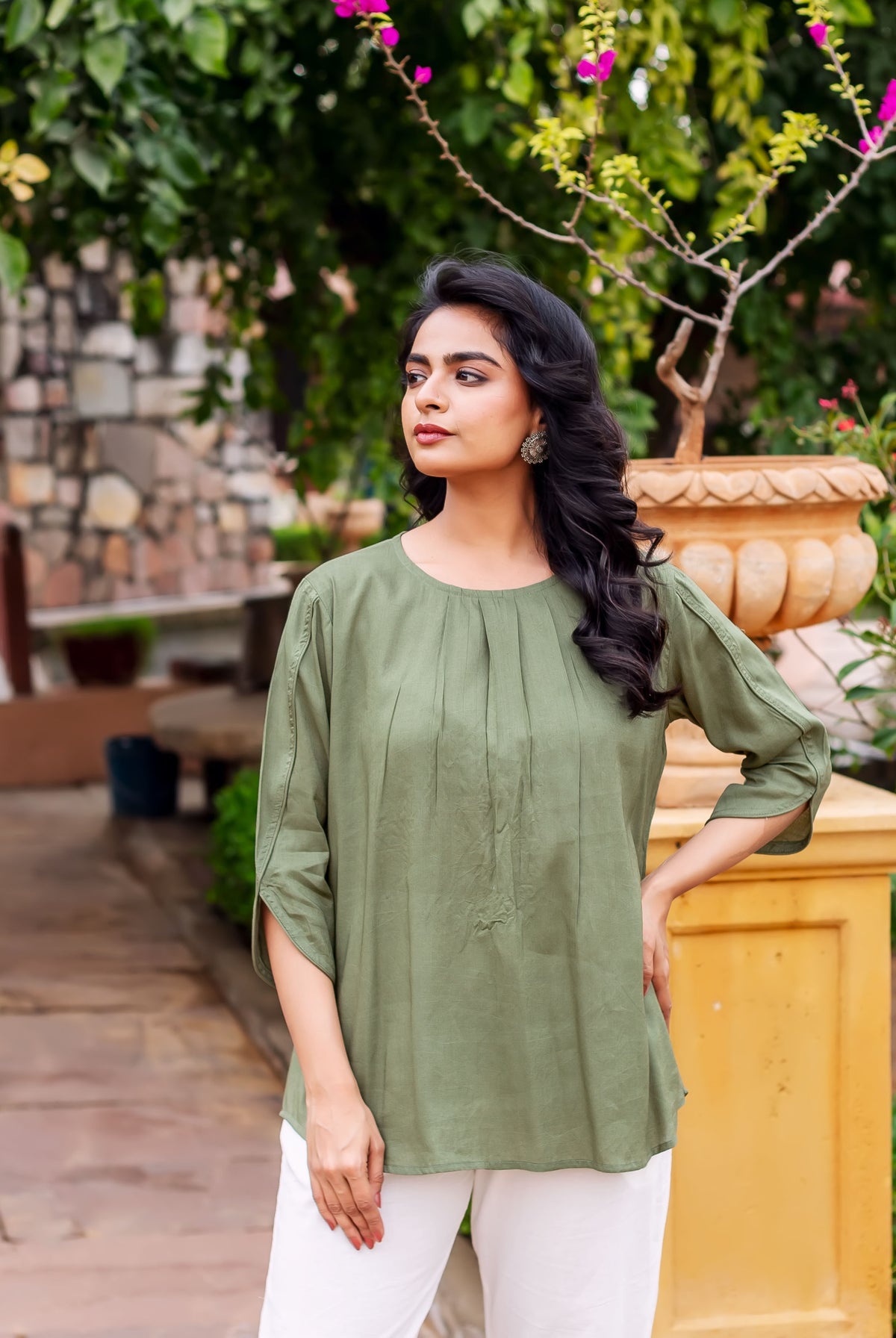 Woman models olive green tunic with pin-tucked yoke and elbow-length sleeves.