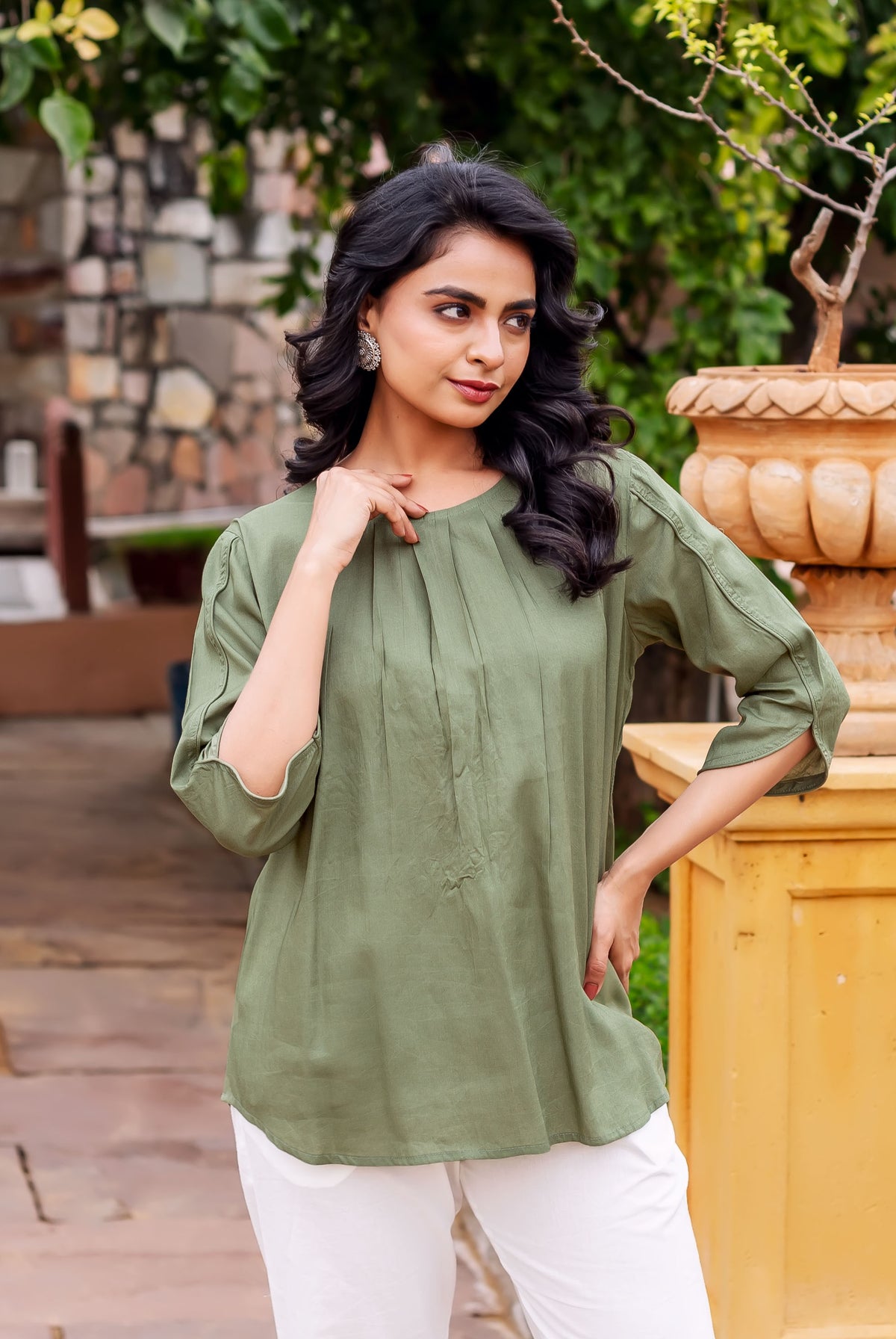 Model wearing a solid olive green tunic with a gathered round neckline and 3/4th sleeves.