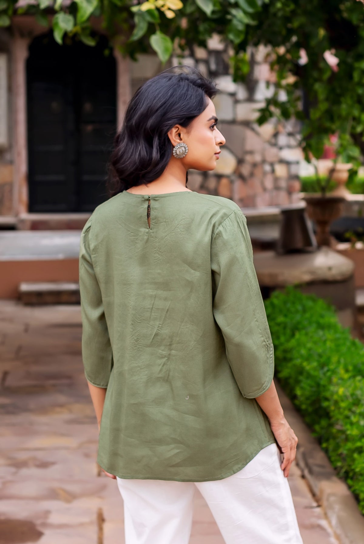 Model in an olive green textured tunic with three-quarter sleeves, seen from the back.