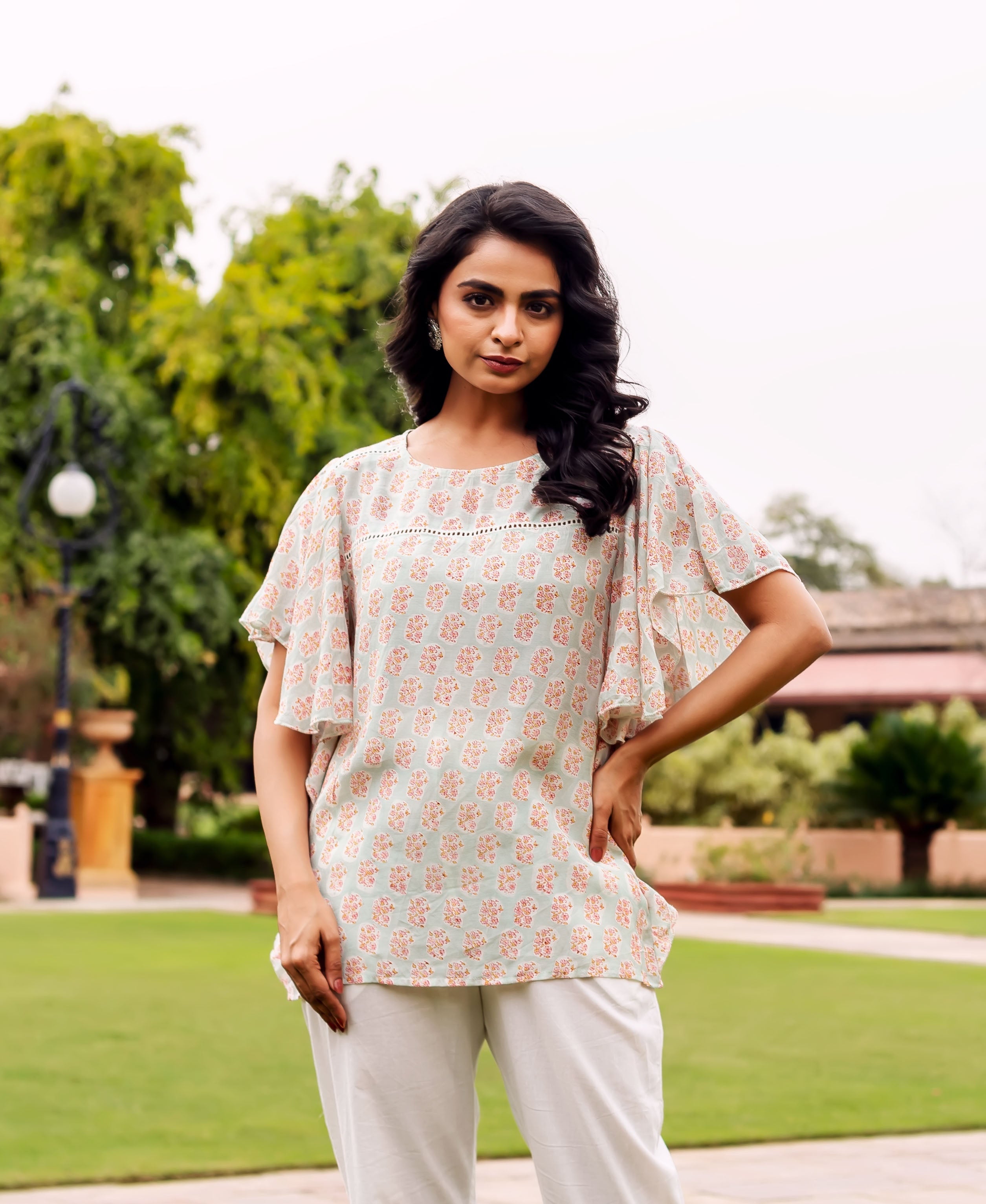 Front view of a model in a mint block-printed tunic with floral pattern and white pants.