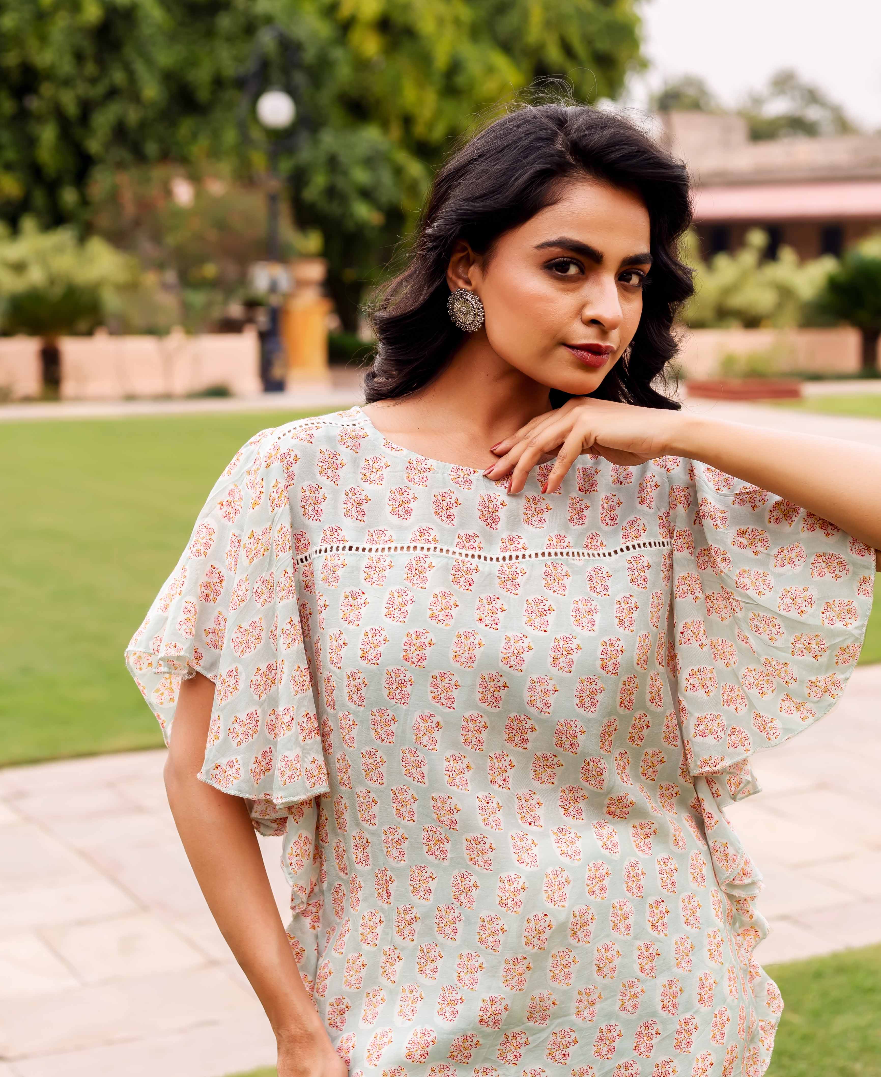 Front view of model wearing a mint green block printed tunic with pink floral pattern.
