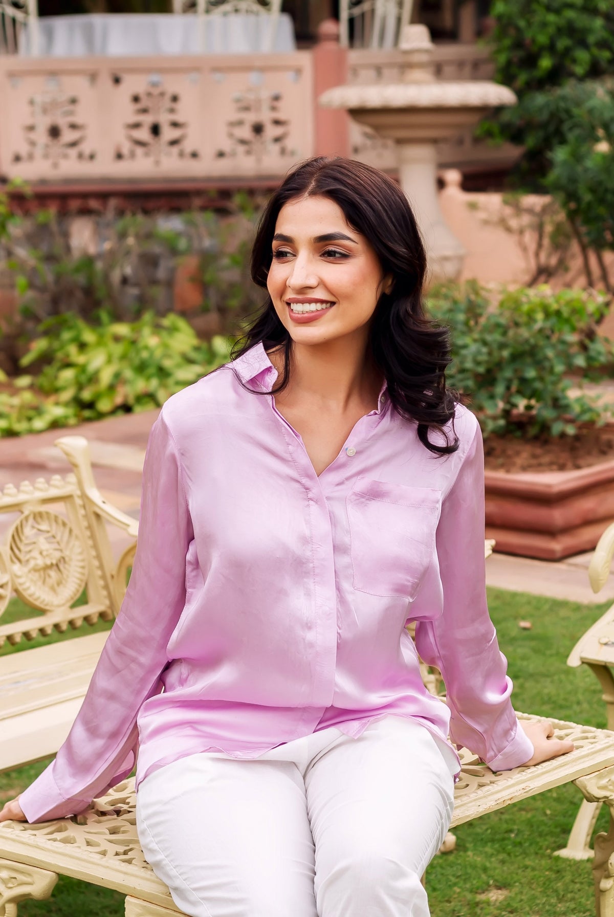 Model seated, wearing a lustrous pink button-down shirt with a chest pocket.