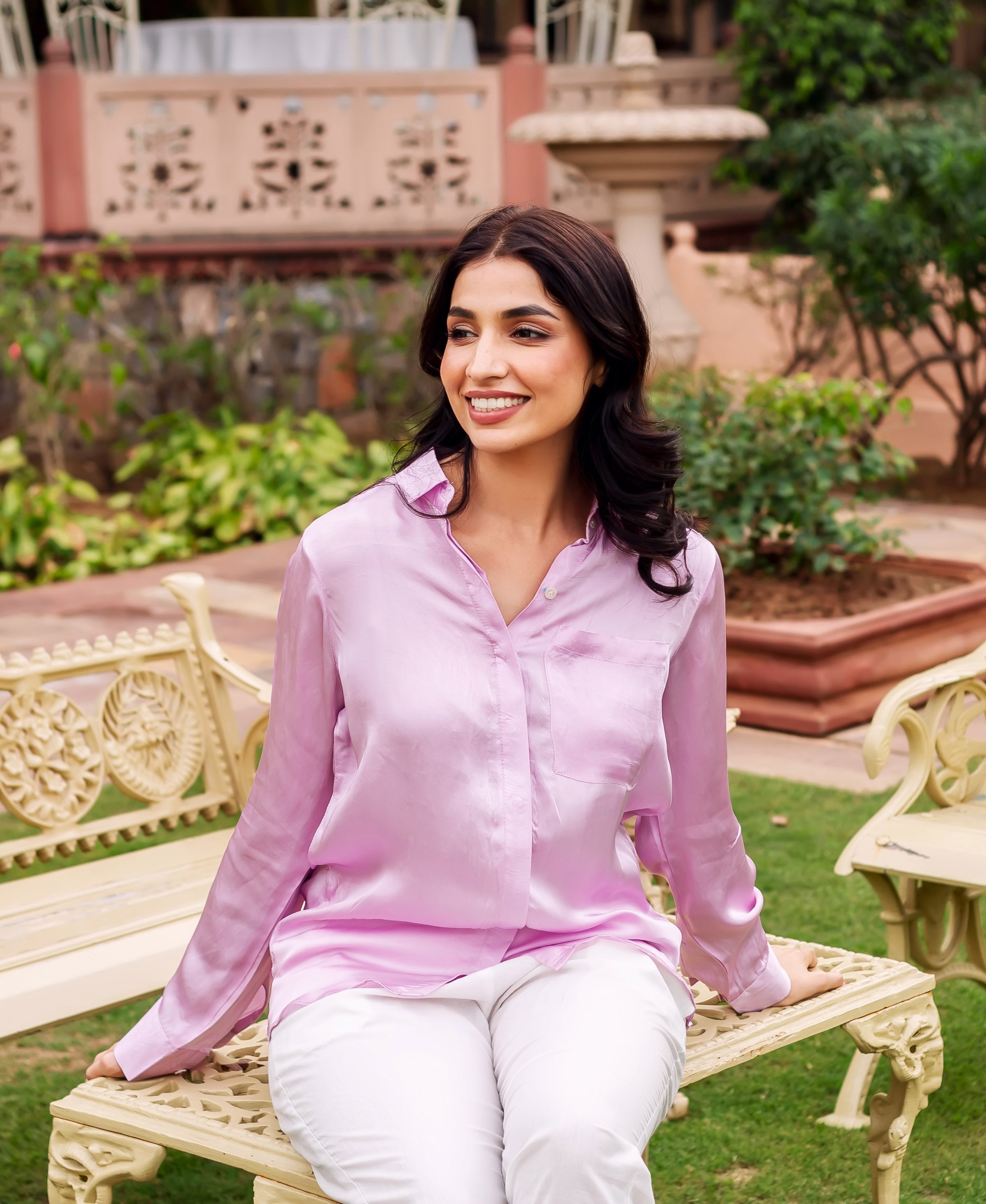 Model seated, wearing a lustrous pink button-down shirt with a chest pocket.