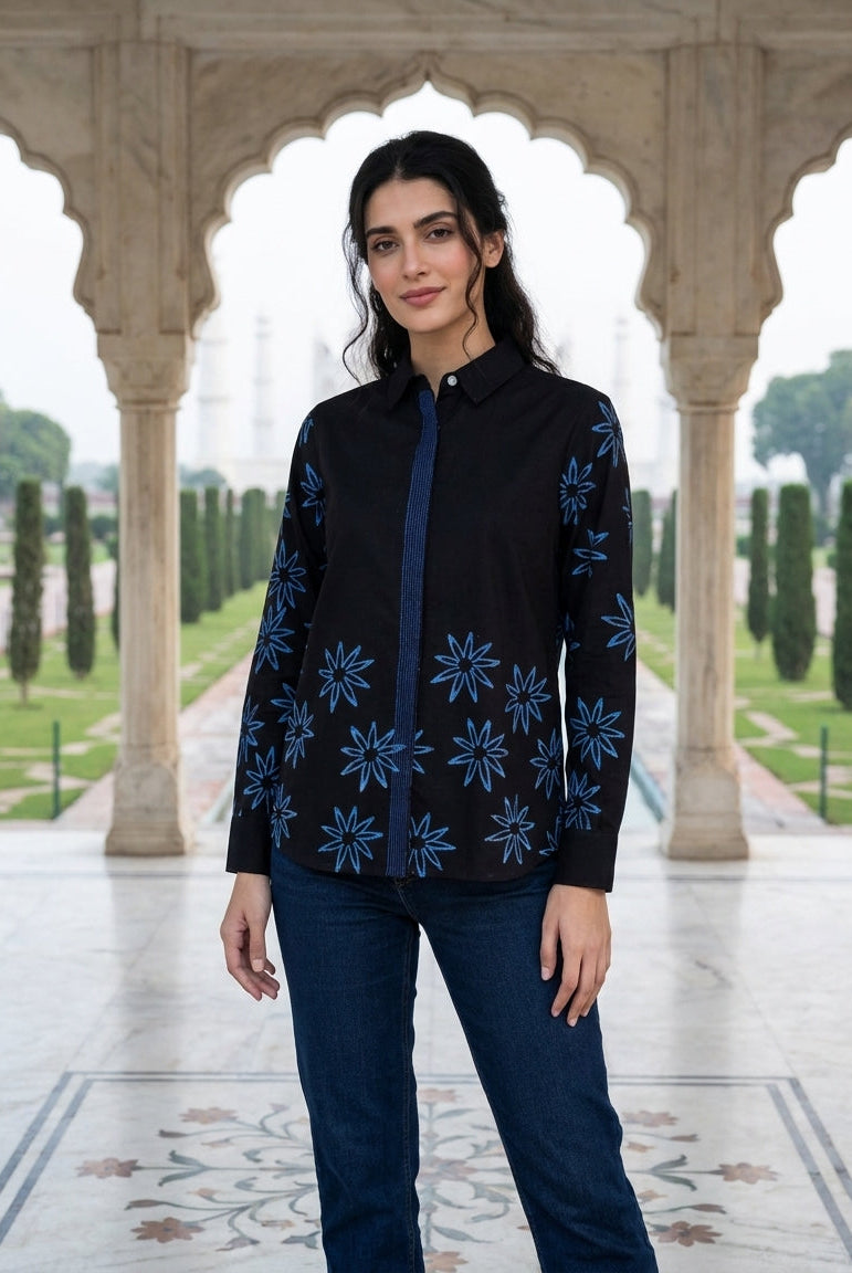 Front, model wearing charcoal black handblock cotton shirt with blue star floral print and jeans.