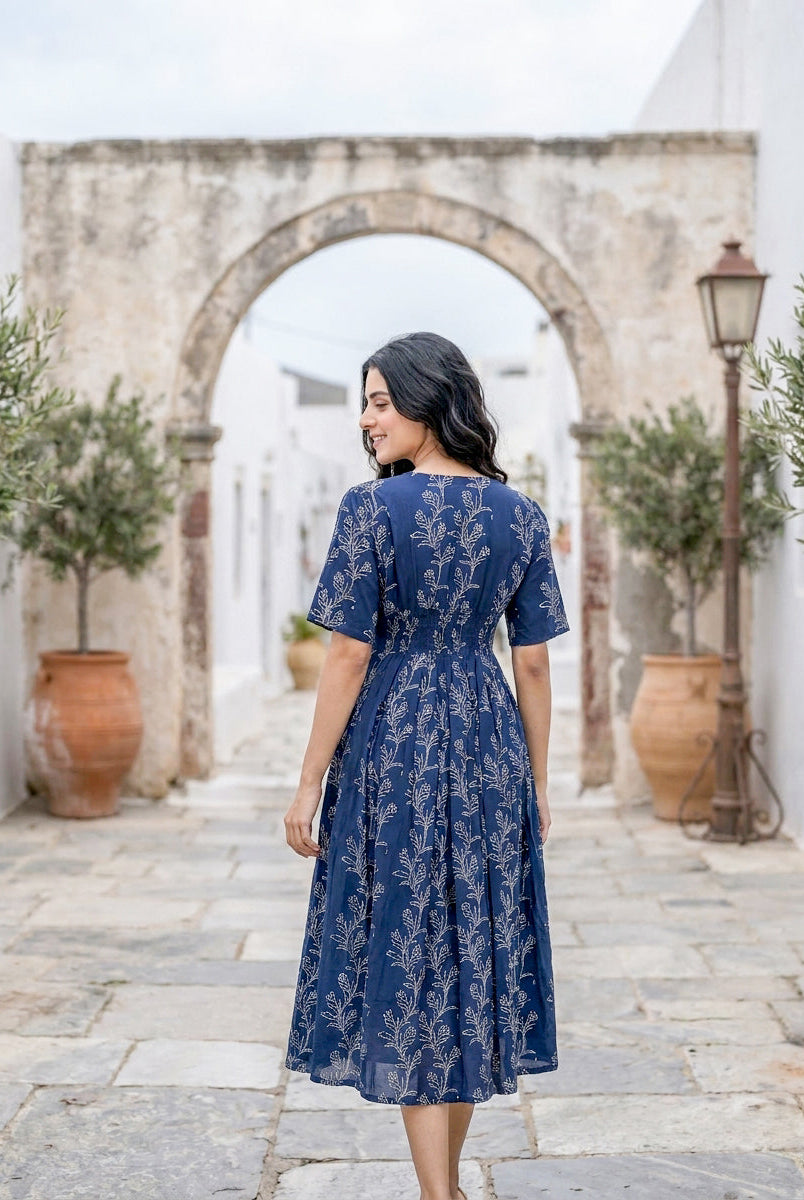 Model from back wearing indigo blue fit-and-flare midi dress with white botanical handblock print.