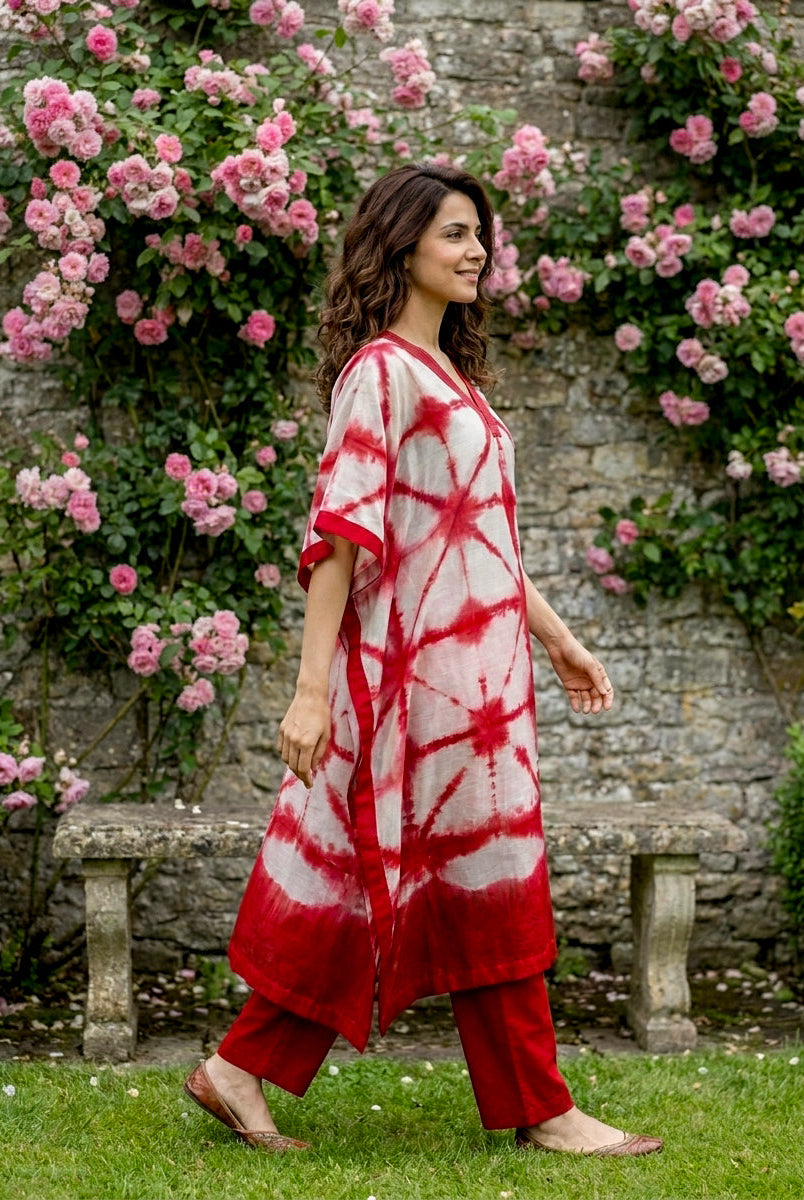 Full side view of woman in red and white tie-dye kaftan and red pants.