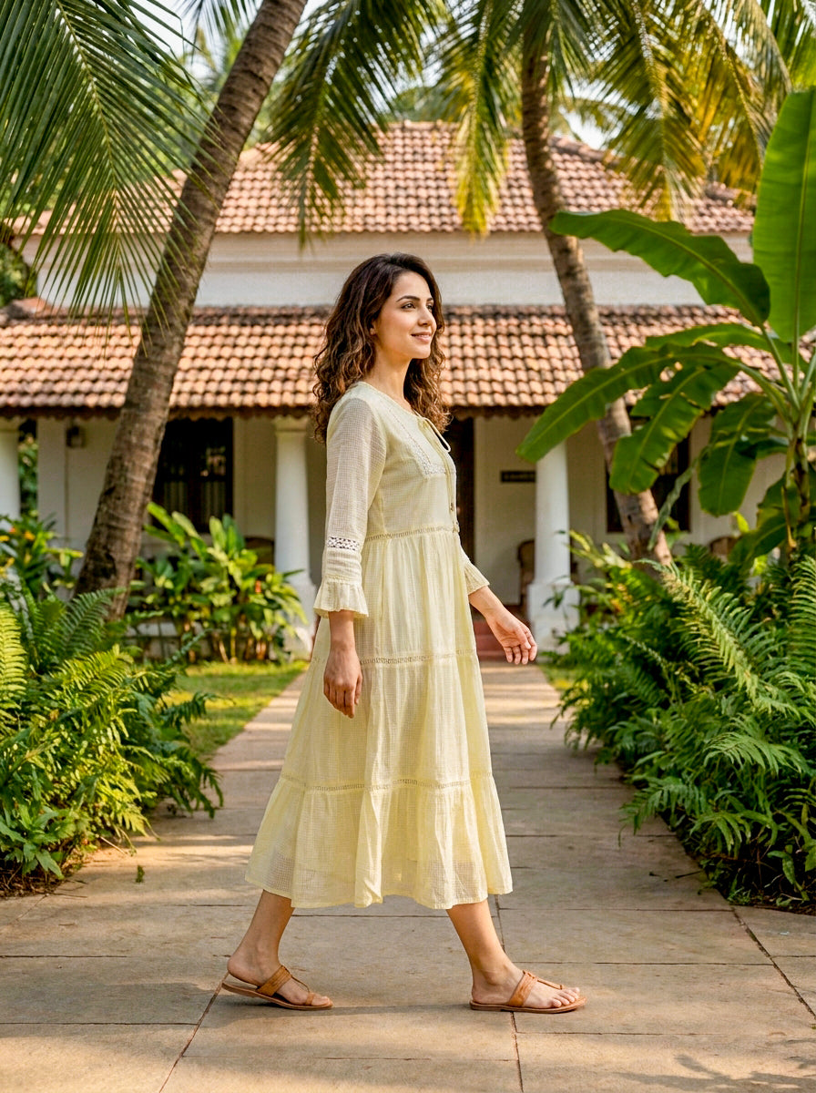A woman in a long, ivory dress with lace inserts and a tiered design.