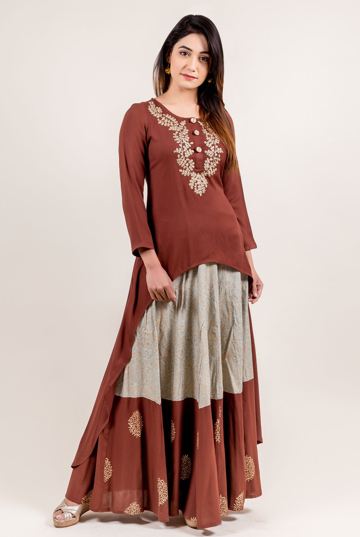 Front view of model in asymmetrical brown embroidered kurta and dual-tone block-printed skirt.