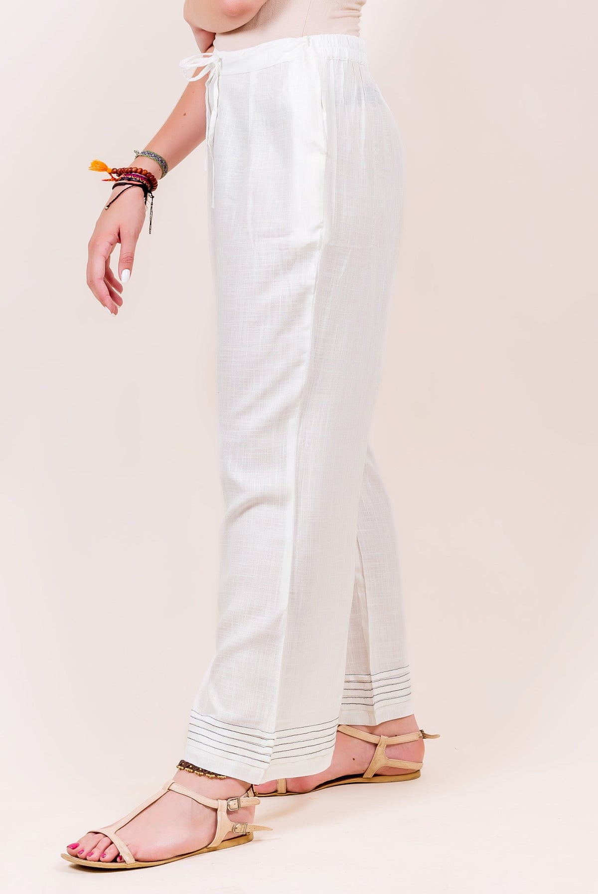 Side view of model in white flared palazzo pants with black stitched hem.