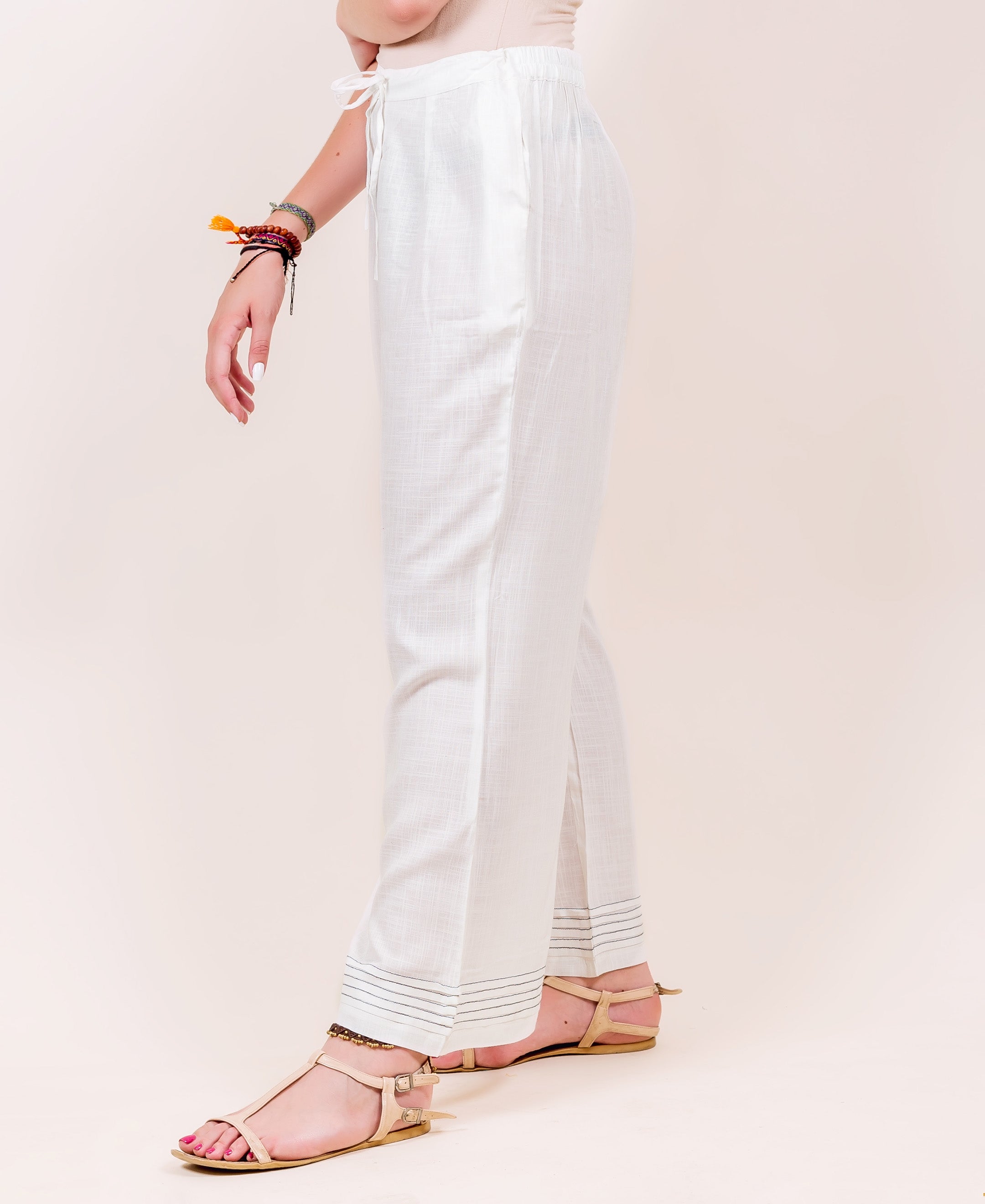 Side view of model in white flared palazzo pants with black stitched hem.