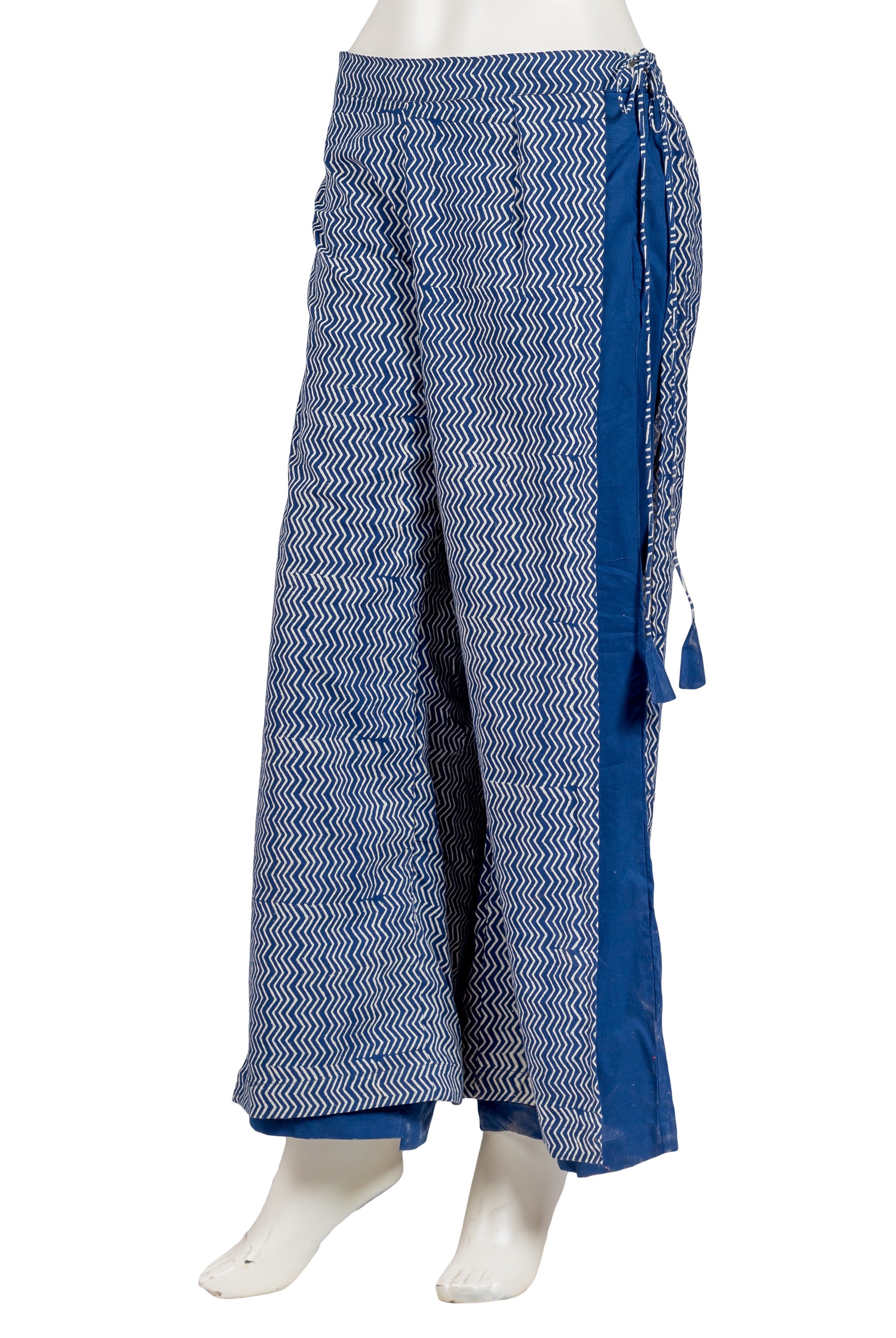 Side view of indigo blue wide-leg pants with white zigzag hand-block print and tassels.