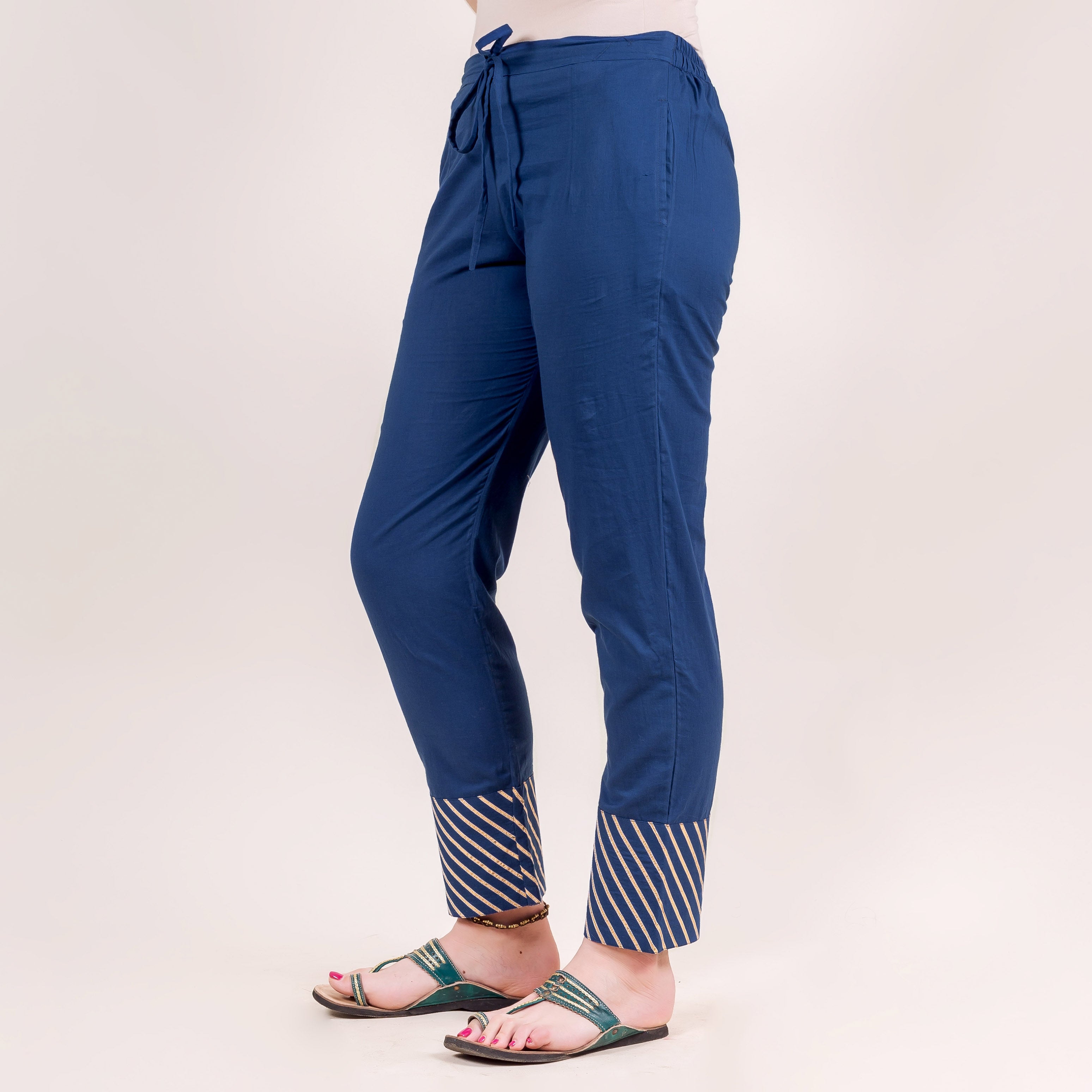 Side view of model in indigo straight pants with hand-block-printed striped cuffs.