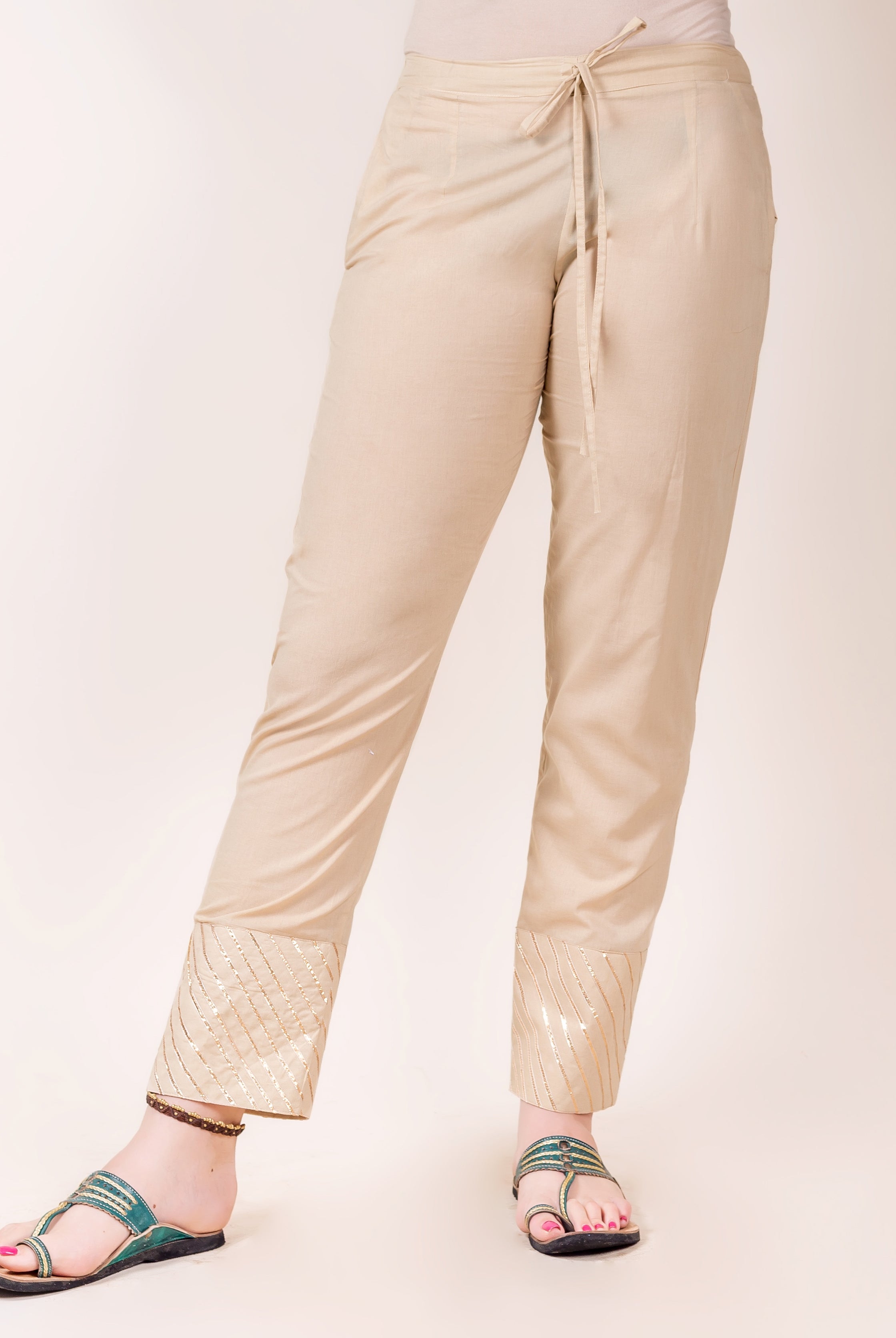 Model wears beige straight pants with golden gota trim detailing at the cuffs.