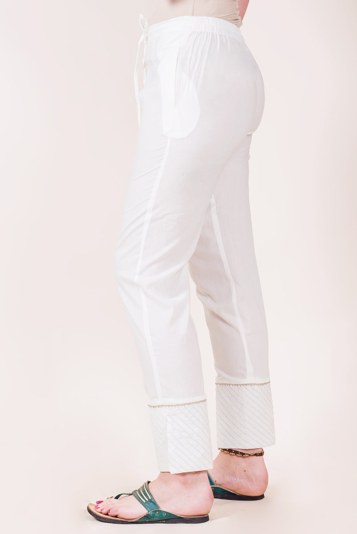 White straight pants on model, side, with kingri lace and gota trim cuffs.