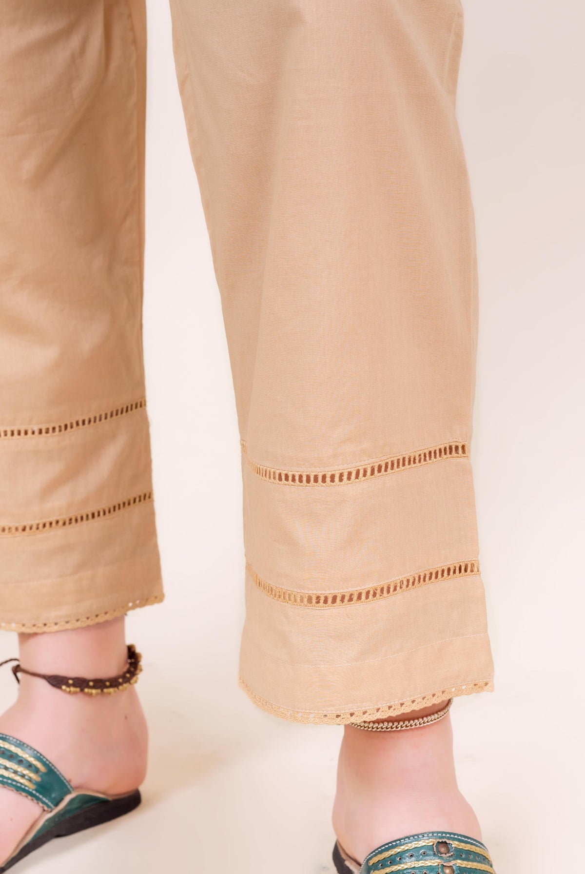 Front view of model's legs wearing beige pants with ladder lace cut-out details.