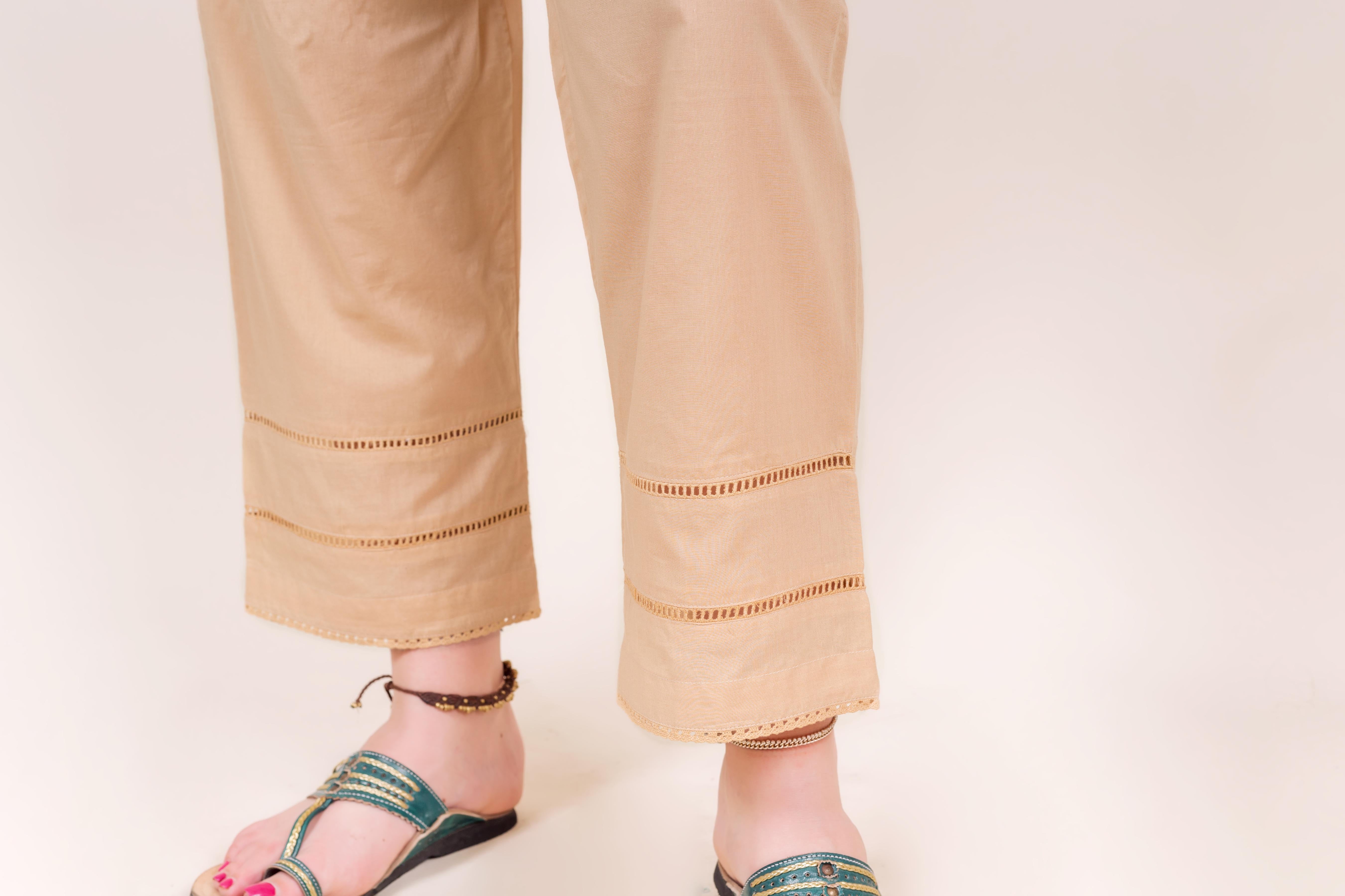 Front view of model's legs wearing beige pants with ladder lace cut-out details.