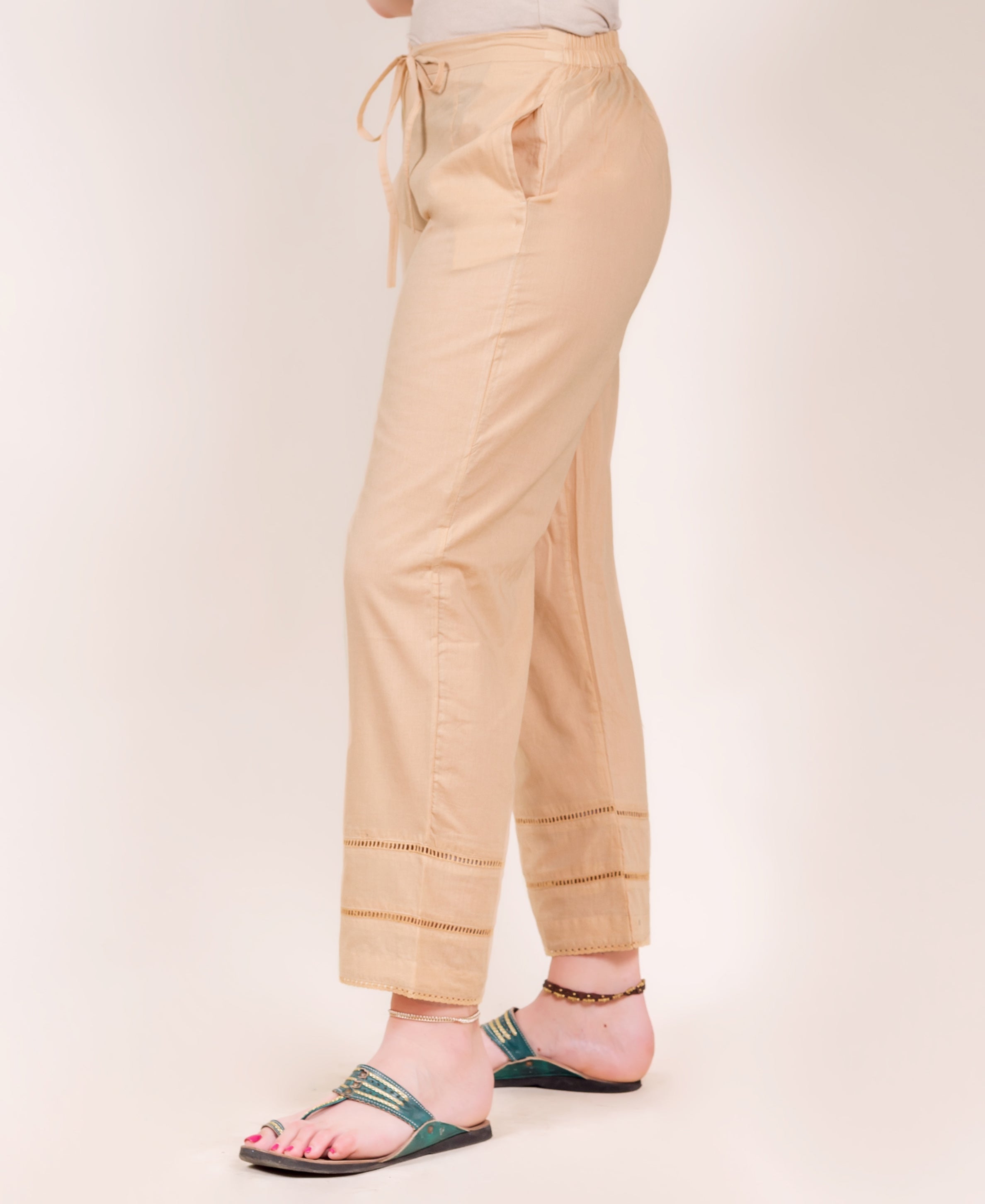 Side view of model wearing beige pants with ladder lace cuffs.