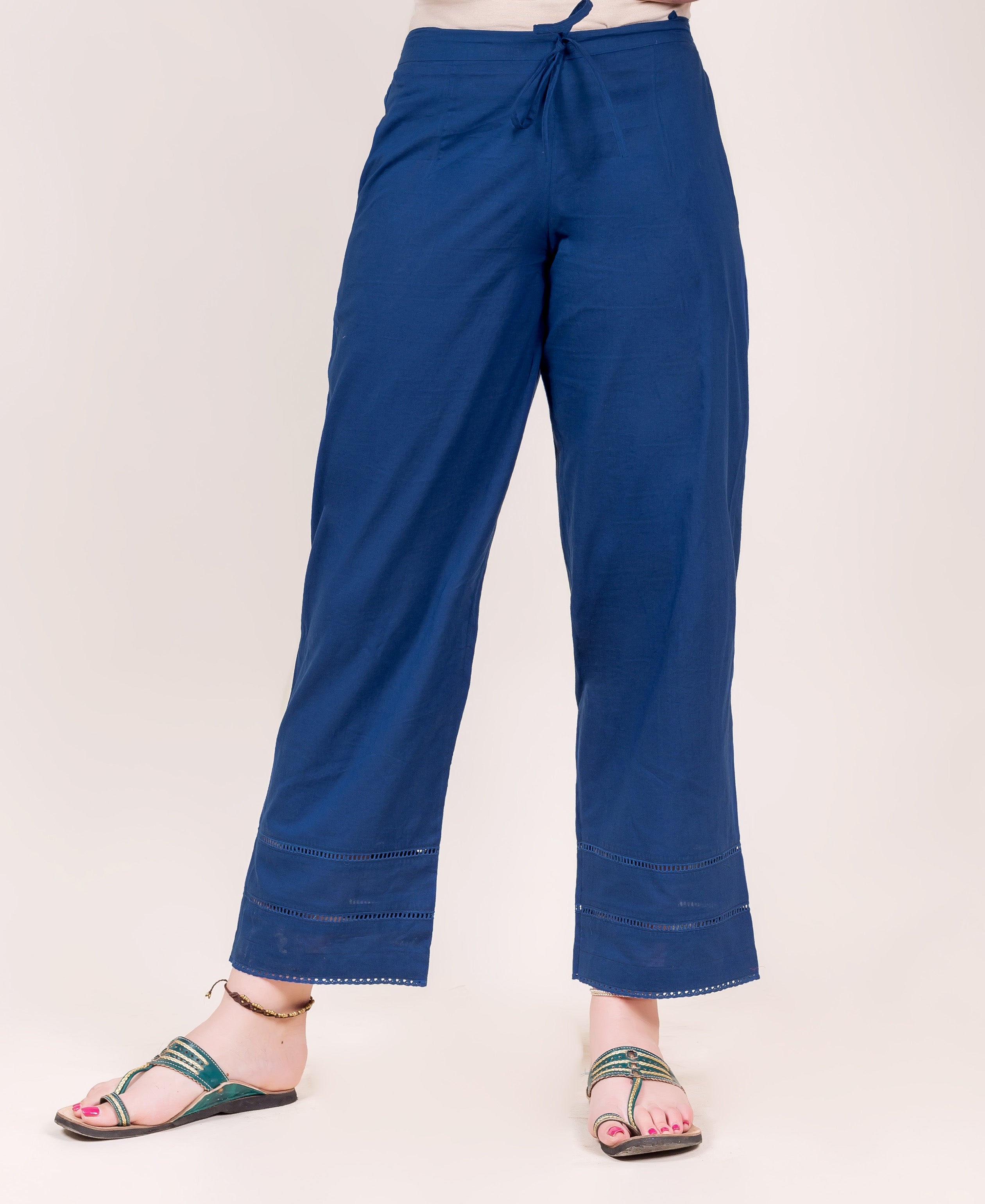 Model wearing indigo blue relaxed pants with drawstring waist and ladder lace trim.