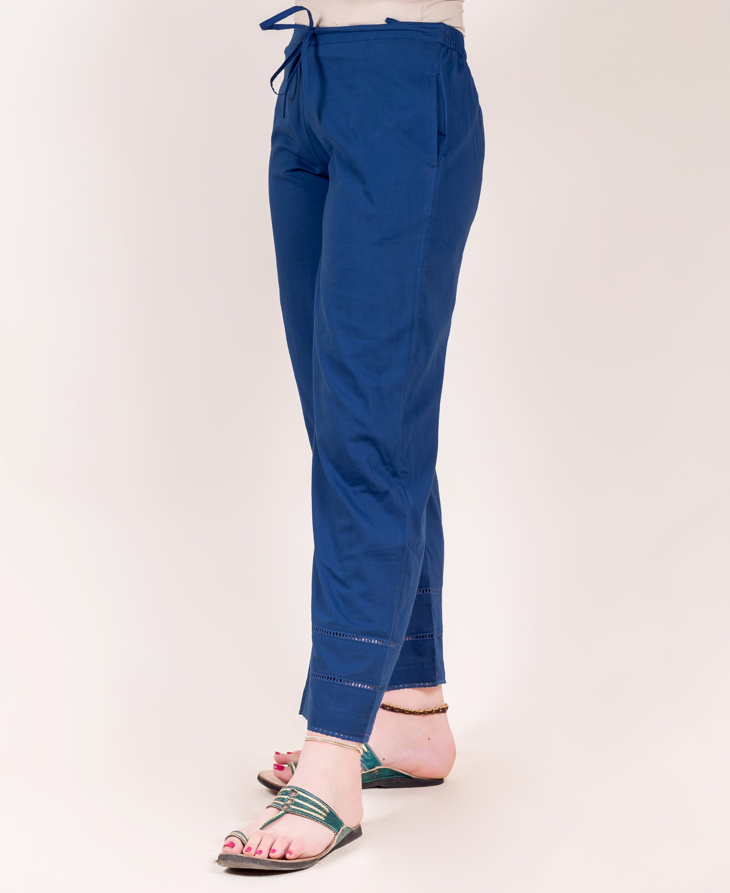 Side view of indigo blue drawstring pants with ladder lace detailed hems on a model.