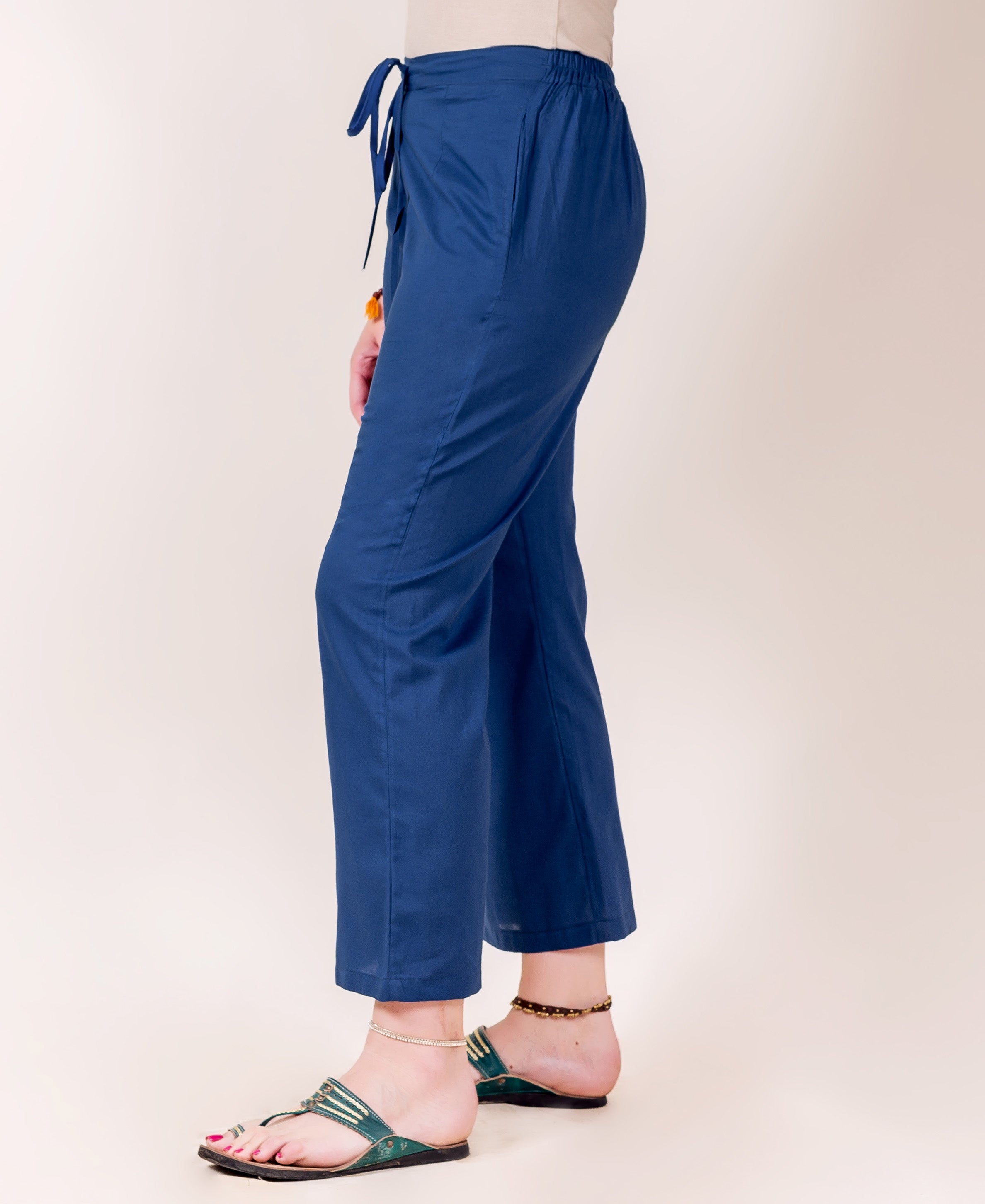 Solid indigo palazzo pants on a model, side view, featuring a drawstring waist.