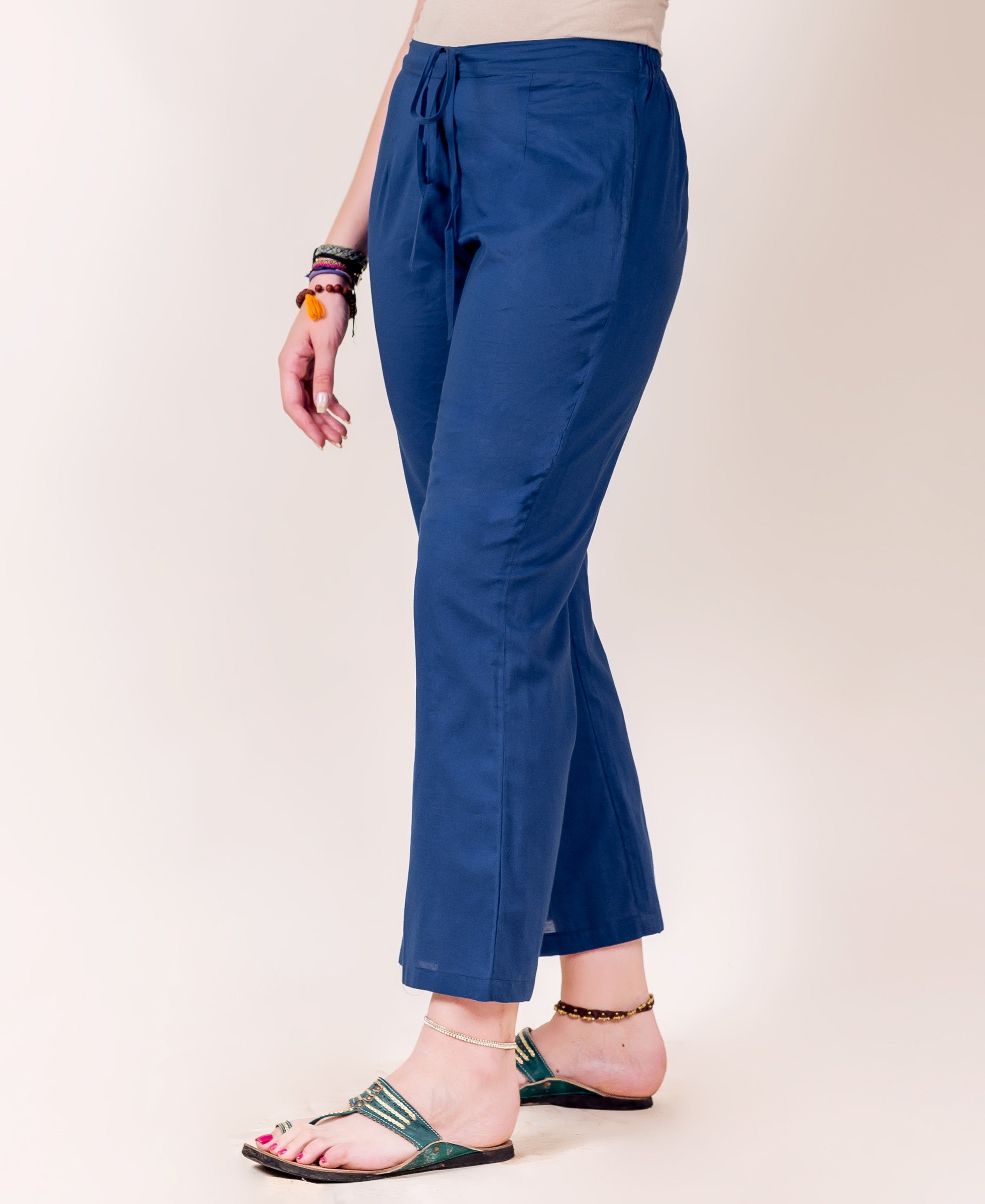 Side view of model wearing solid indigo blue drawstring palazzo pants, ankle-length.