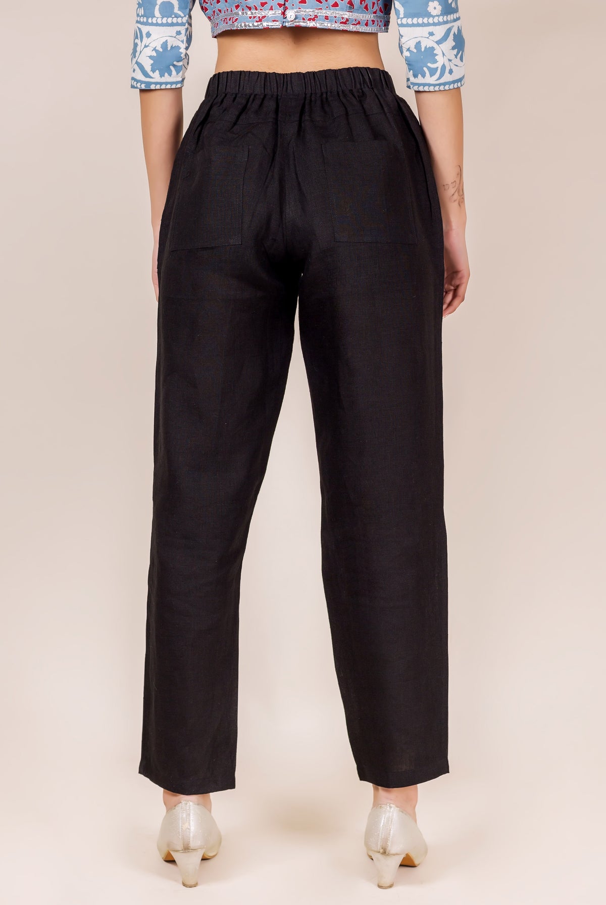 Black linen solid pants on model, back view, with elastic waistband and pockets.