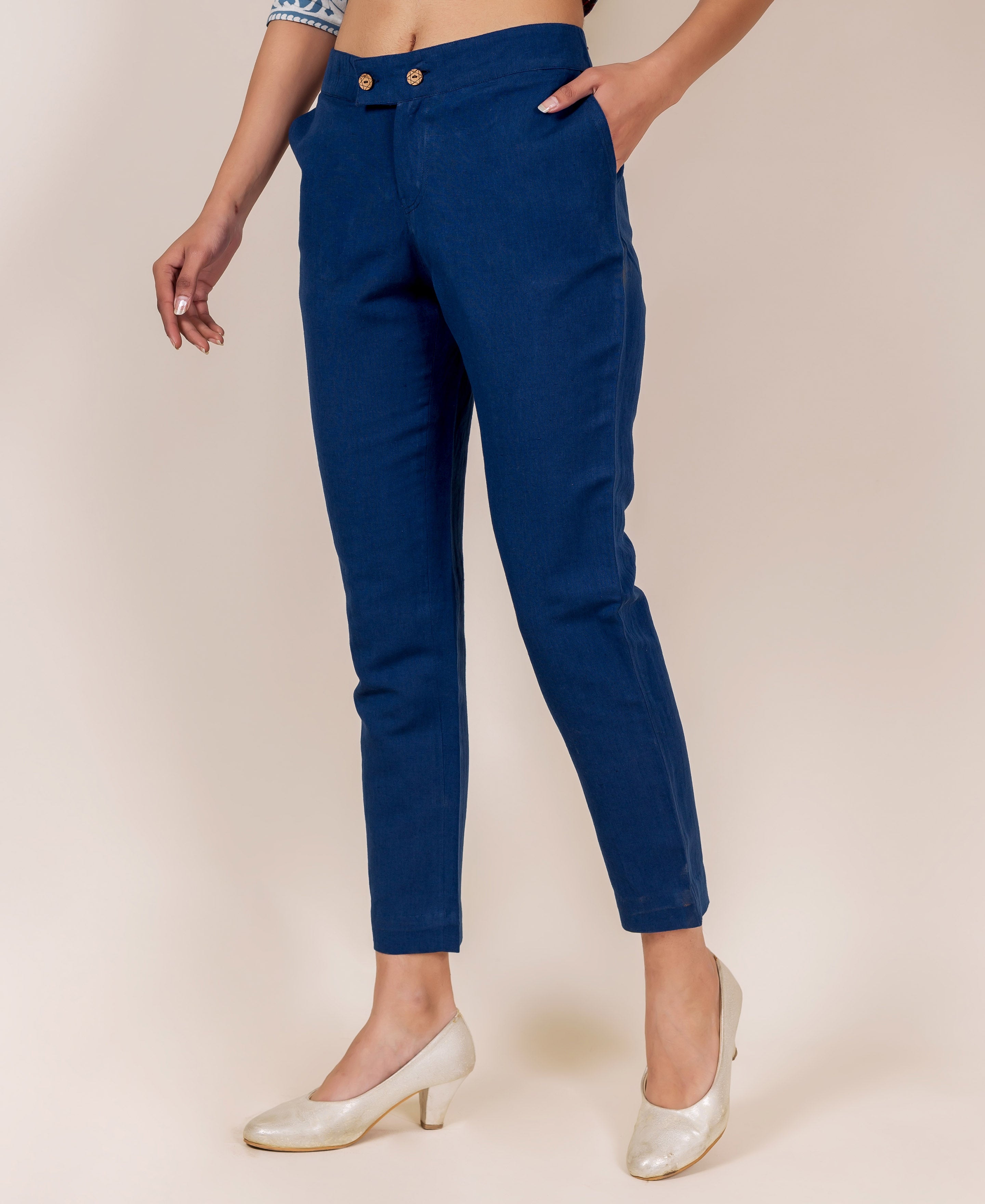 Model in indigo blue solid narrow bottom pants with a double button waist.