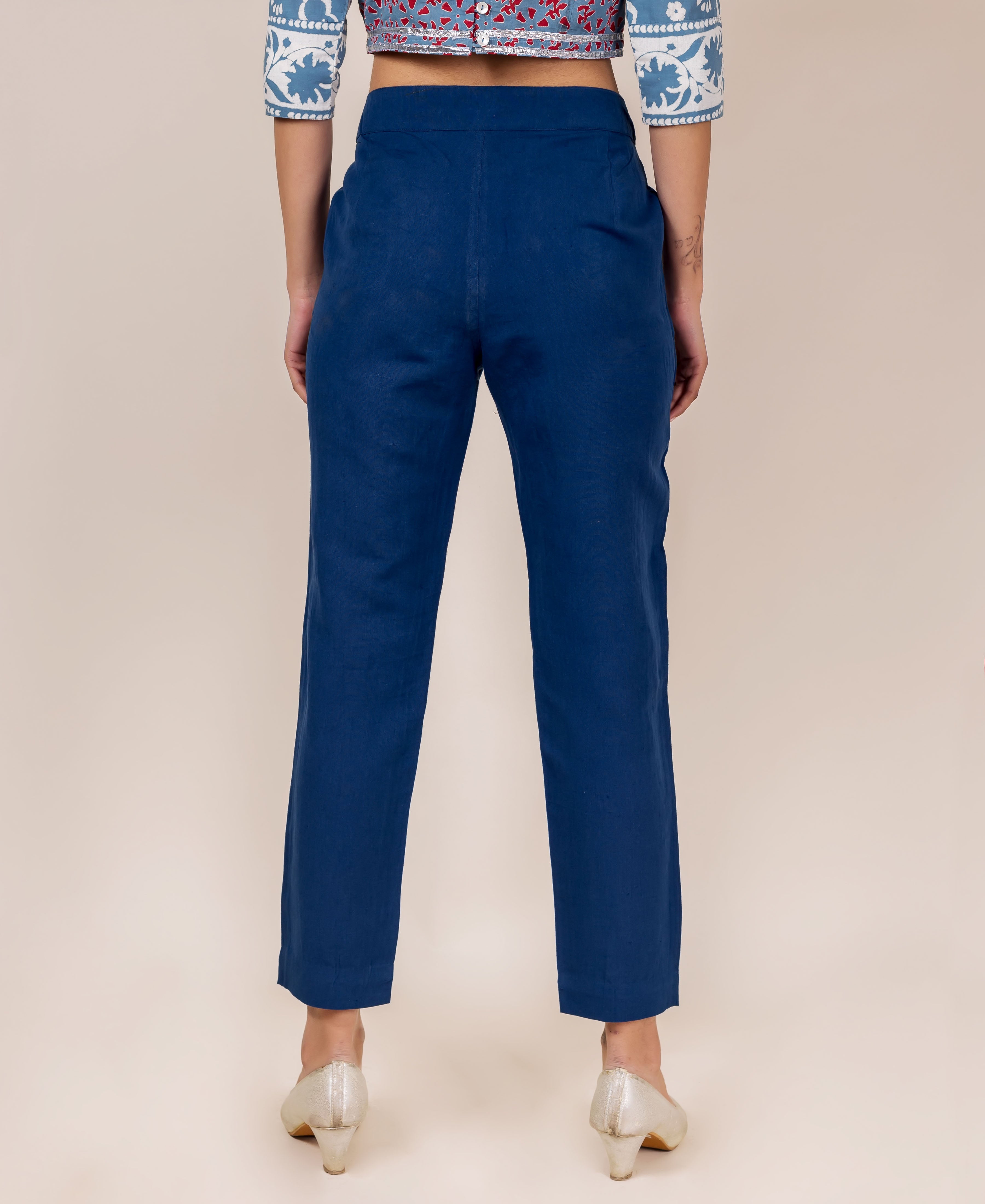 Back view of model wearing solid indigo linen narrow bottom pants and printed crop top.