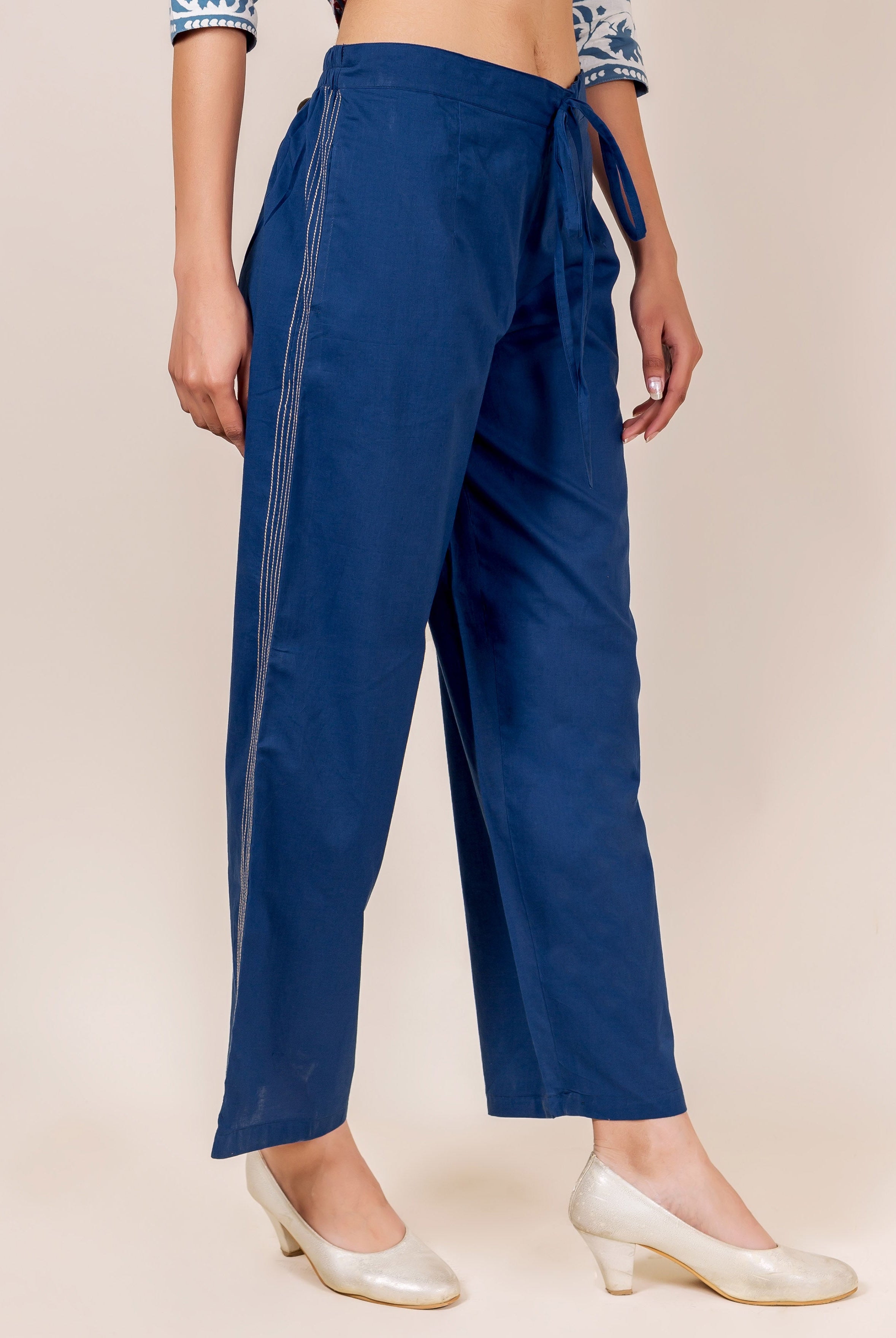 Partial view of model in indigo blue embroidered palazzo pants with drawstring waist.
