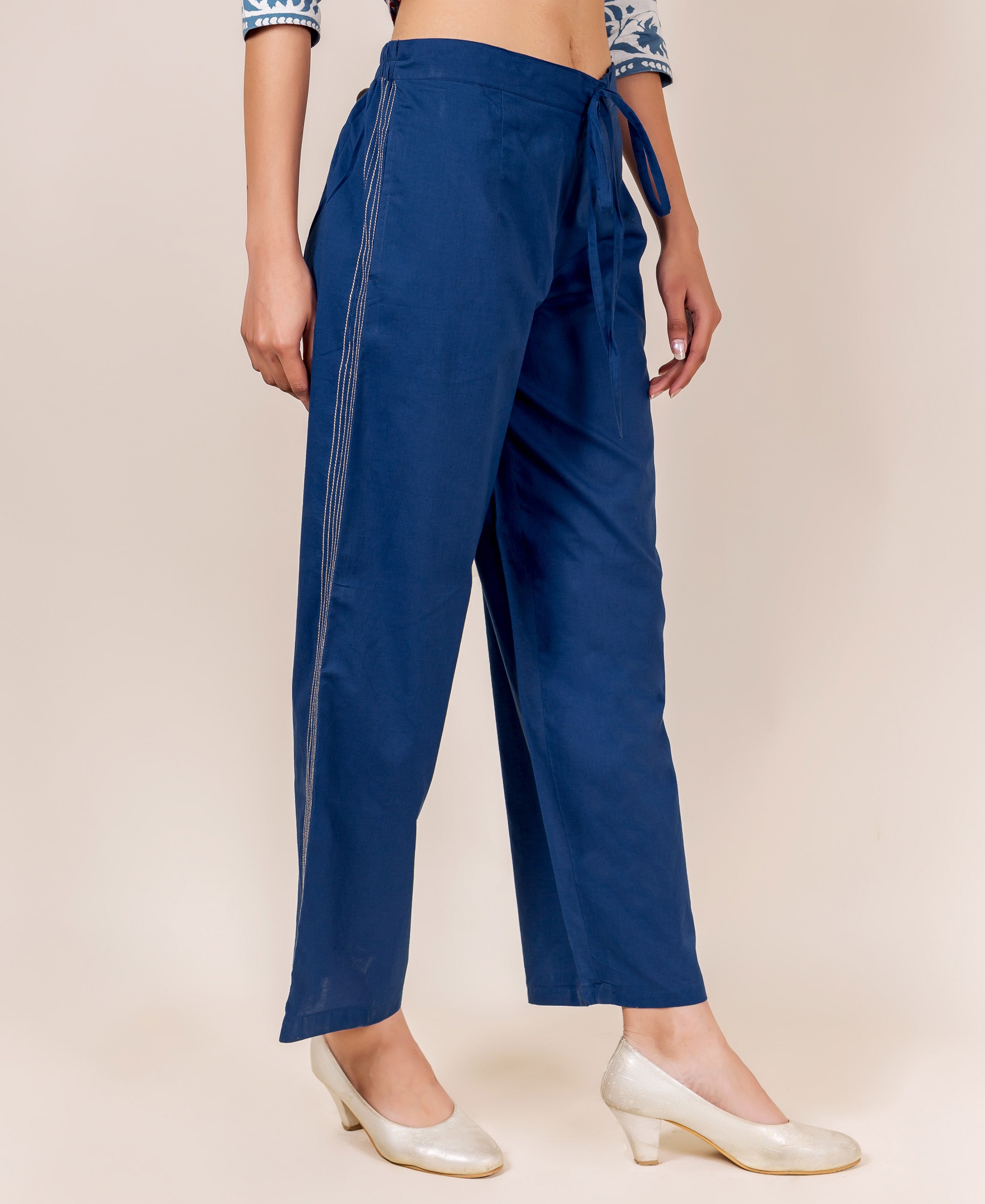 Partial view of model in indigo blue embroidered palazzo pants with drawstring waist.