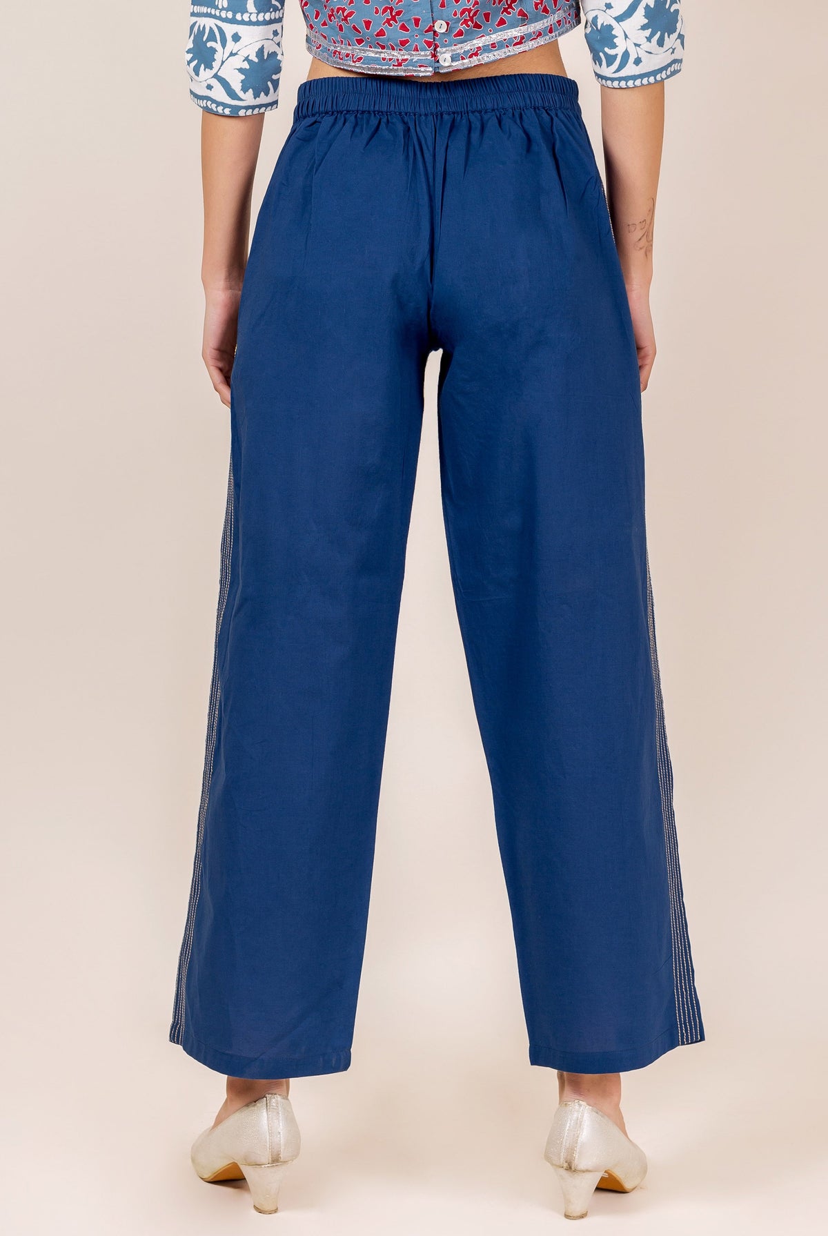 A model wearing indigo palazzo pants with white embroidery.