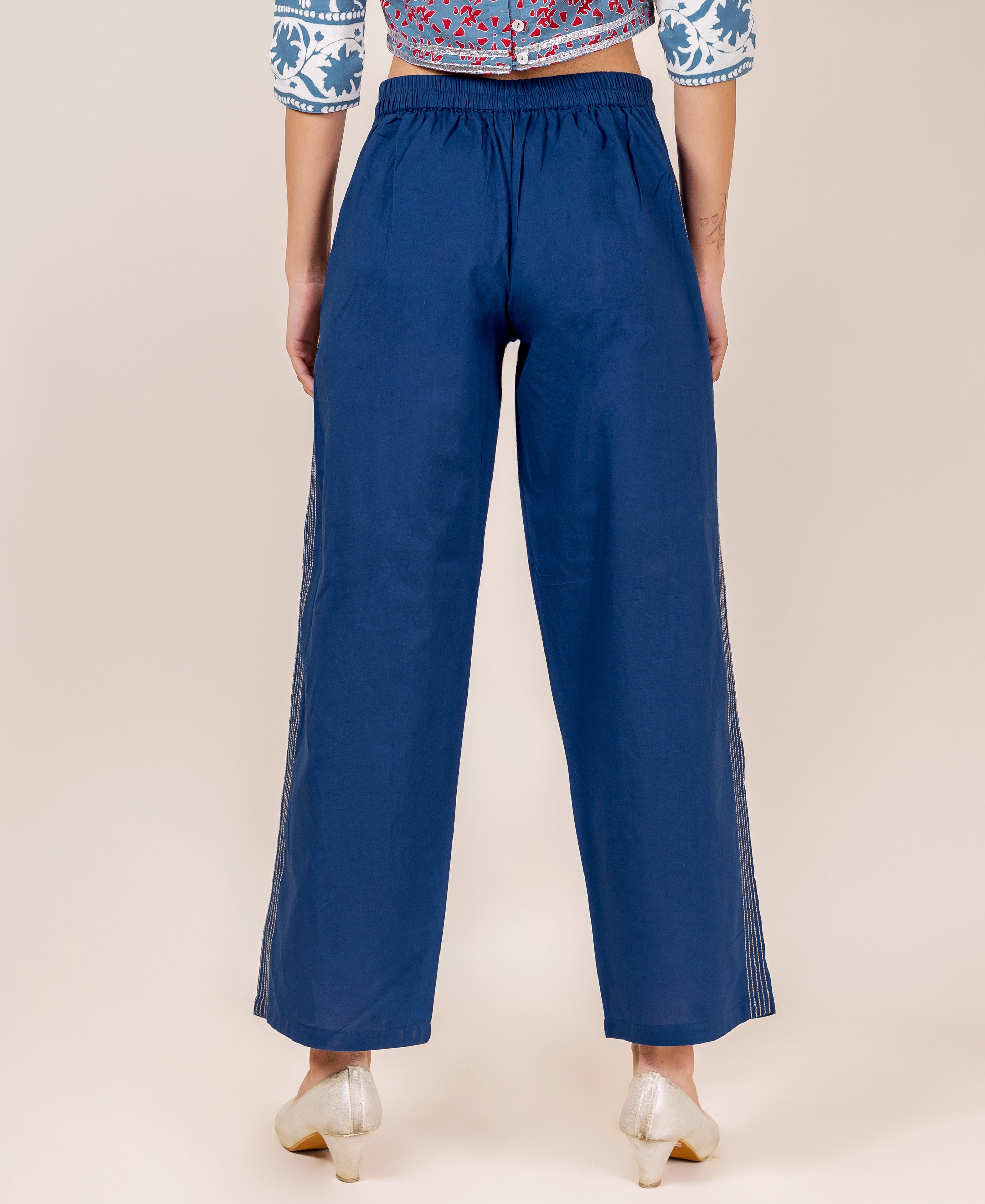 A model wearing indigo palazzo pants with white embroidery.