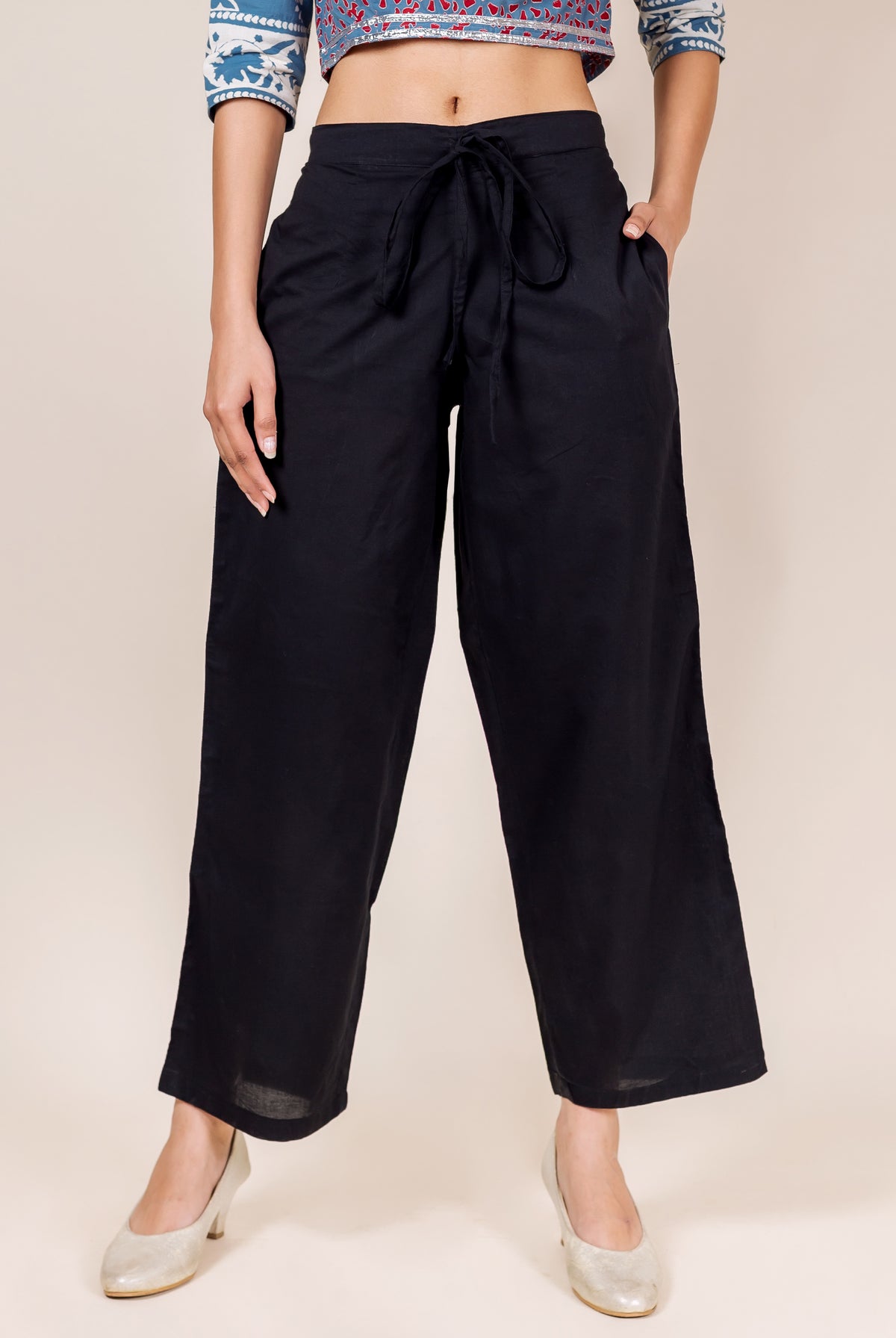 Front view of a model wearing black cotton palazzo pants with a tie-up waist and pockets.