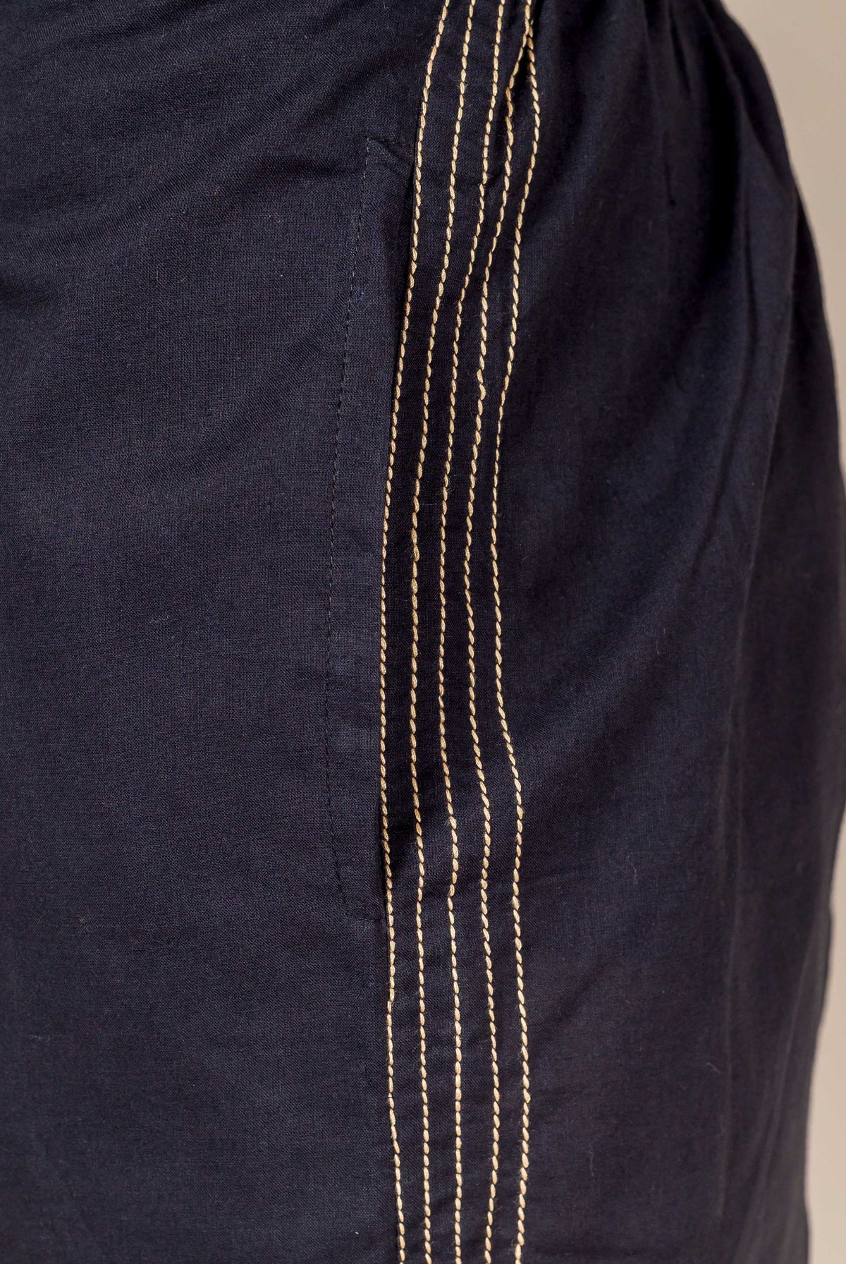 Close-up of black cotton palazzo pants featuring five irregular tan vertical embroidered lines.