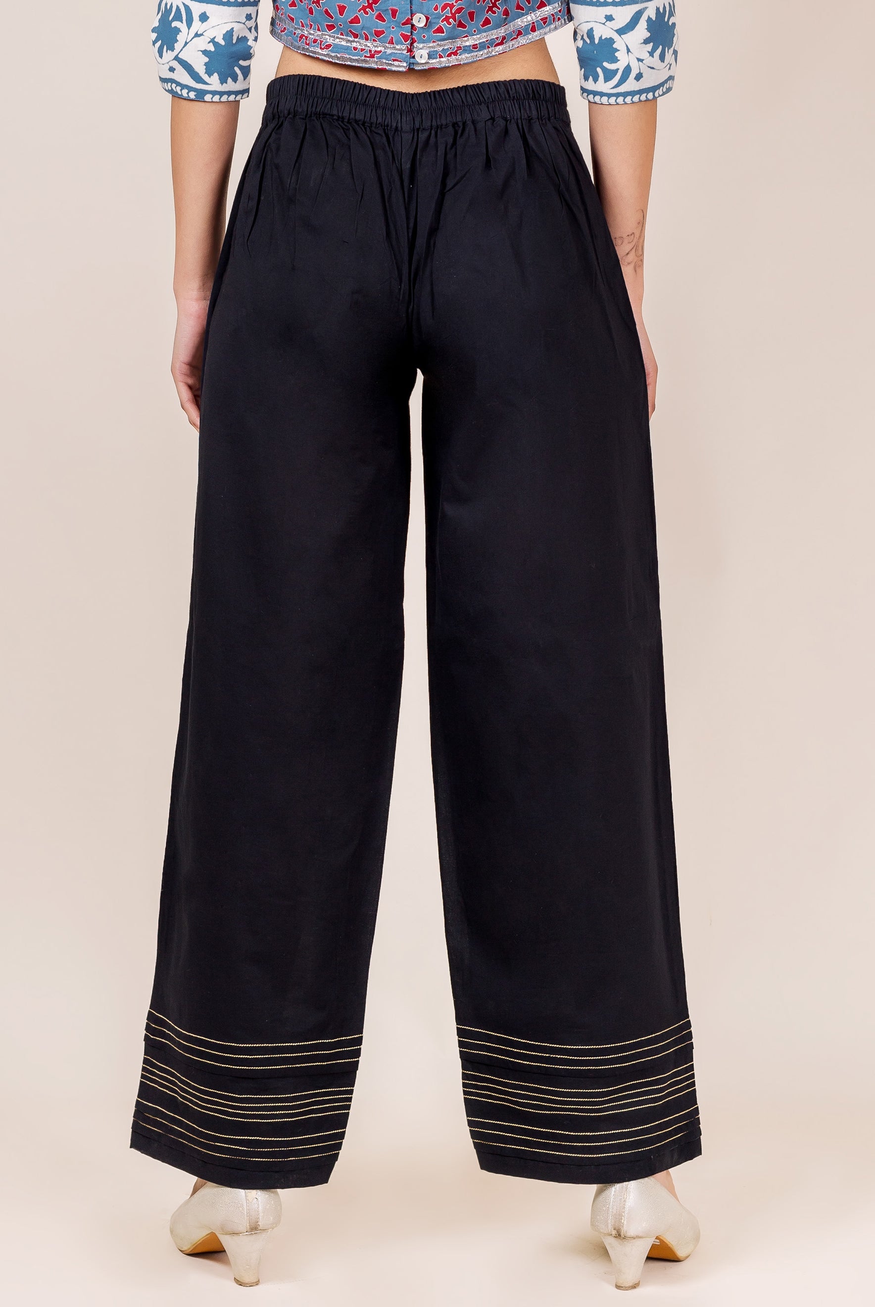 Black palazzo pants with gold embroidery on a model.