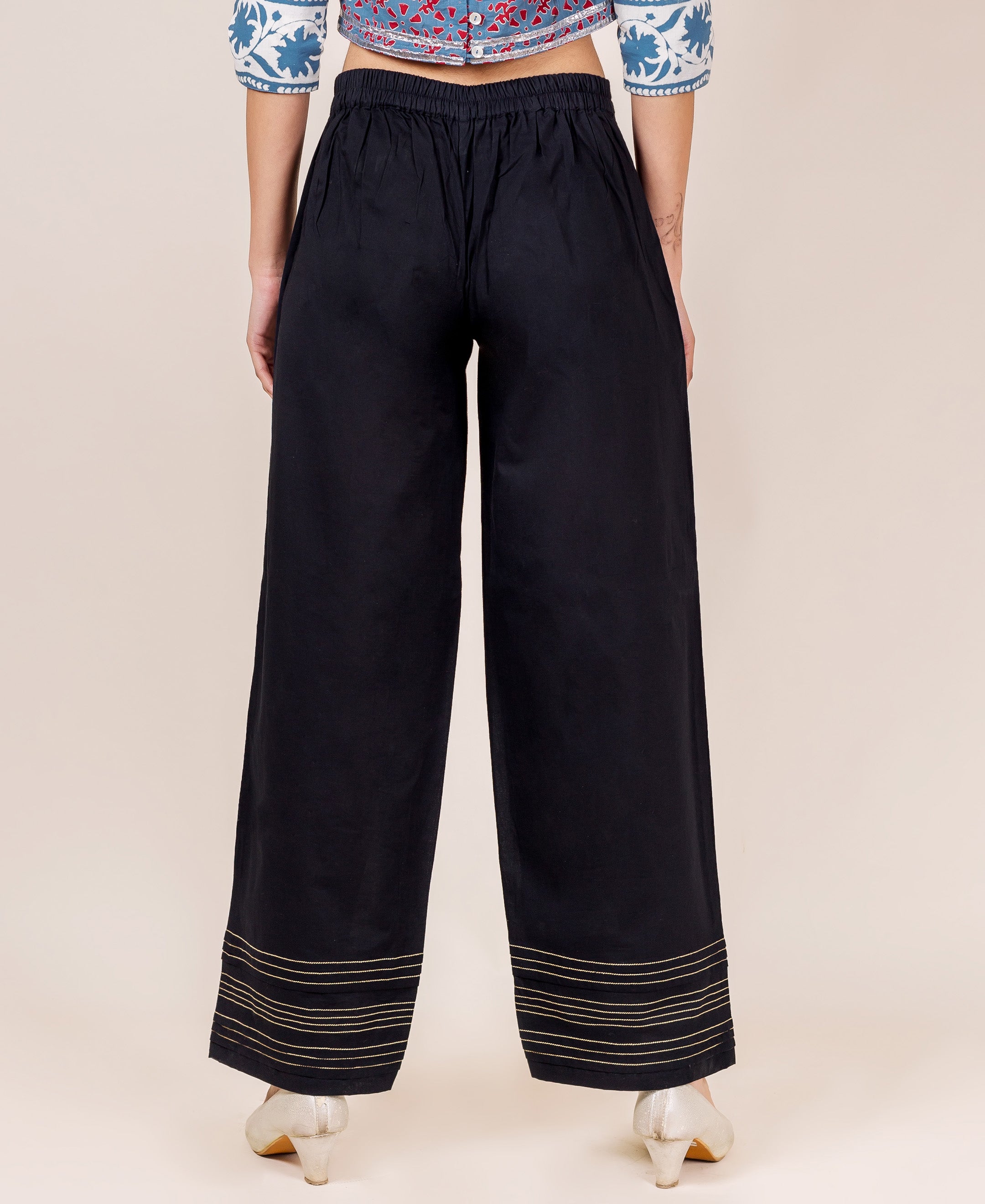 Black palazzo pants with gold embroidery on a model.