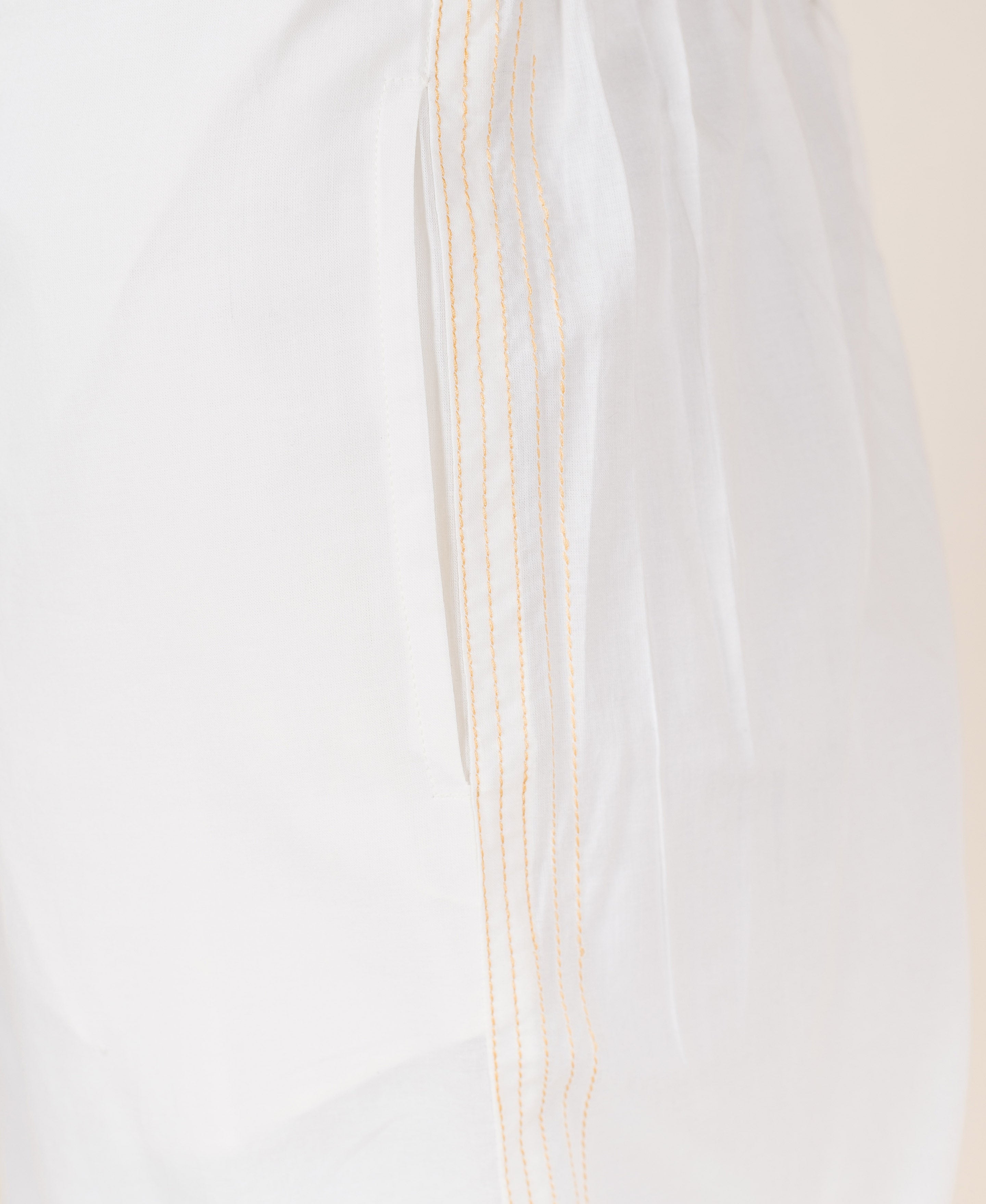 White palazzo pants with embroidered golden yellow stripes down the side.