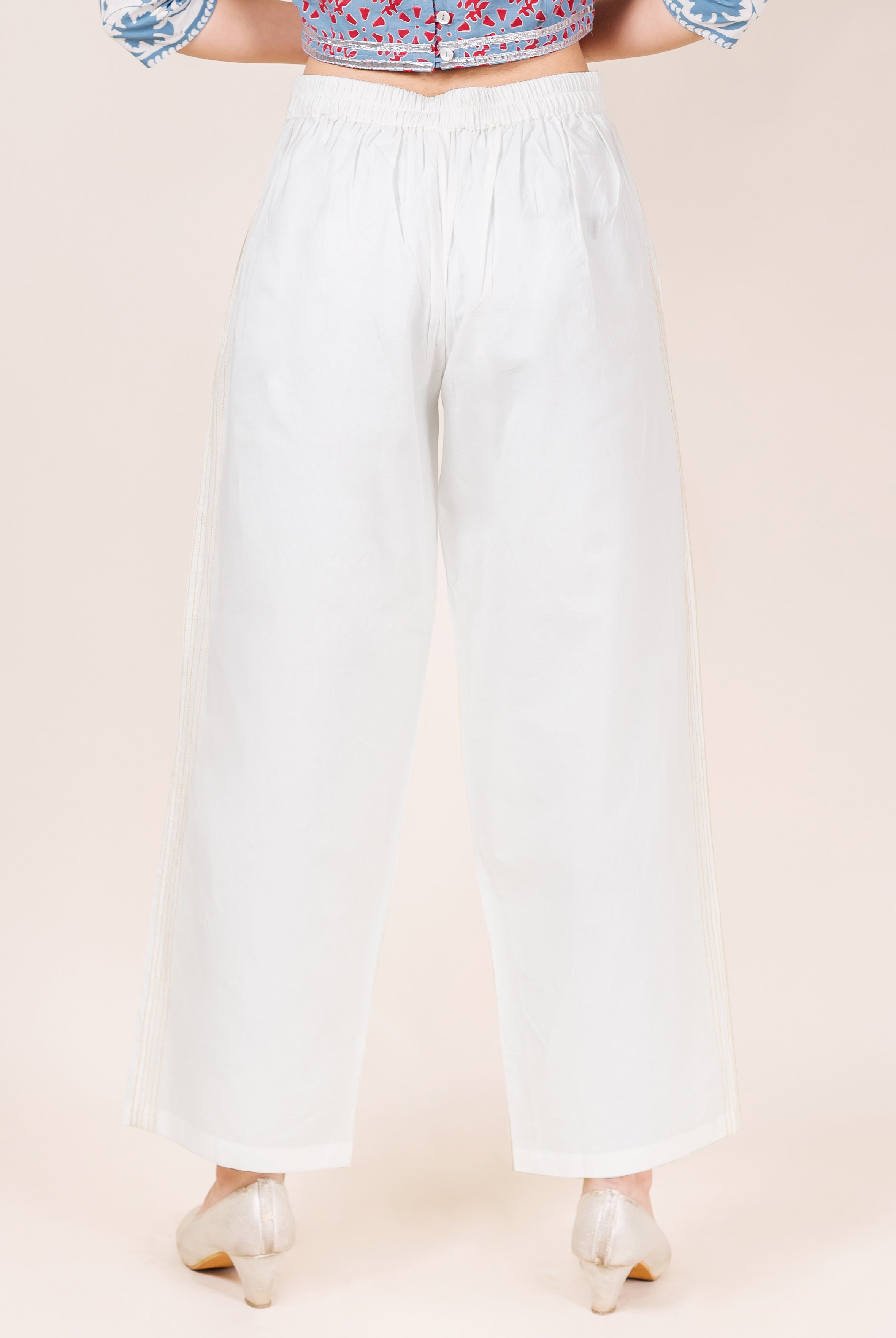 White wide-leg palazzo pants on model, back view, with elasticated waist and subtle embroidery.