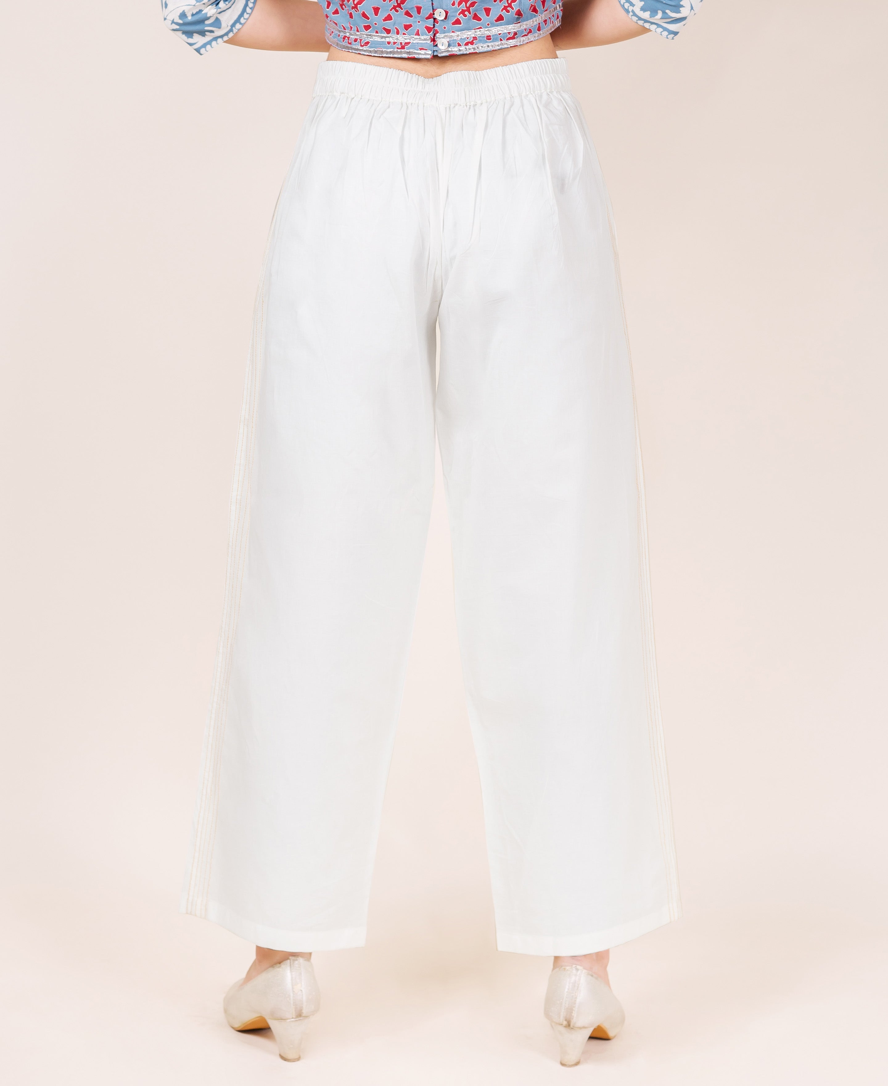 White wide-leg palazzo pants on model, back view, with elasticated waist and subtle embroidery.