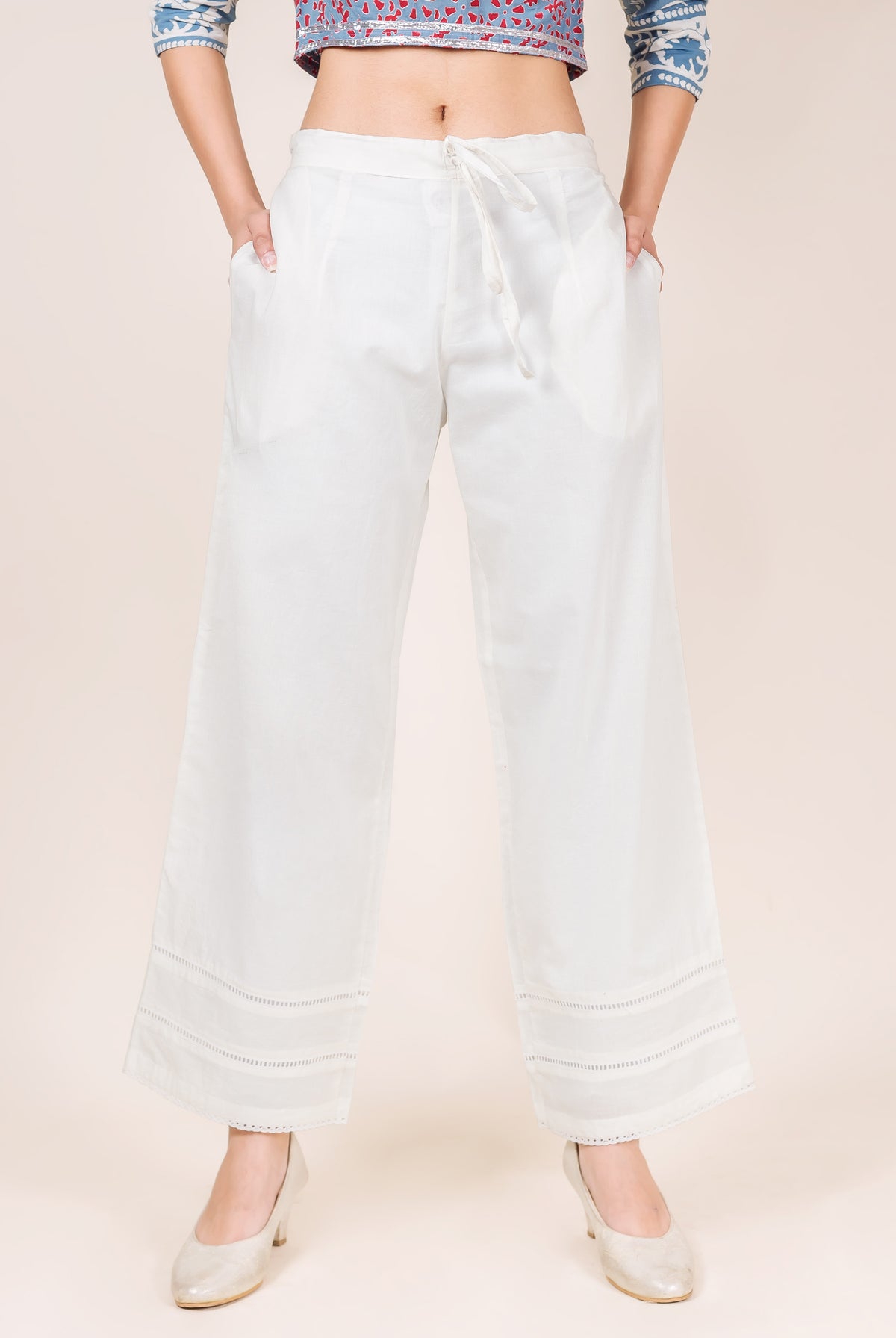 Model wearing white solid palazzo pants with a drawstring waist and lacy detailed hem.