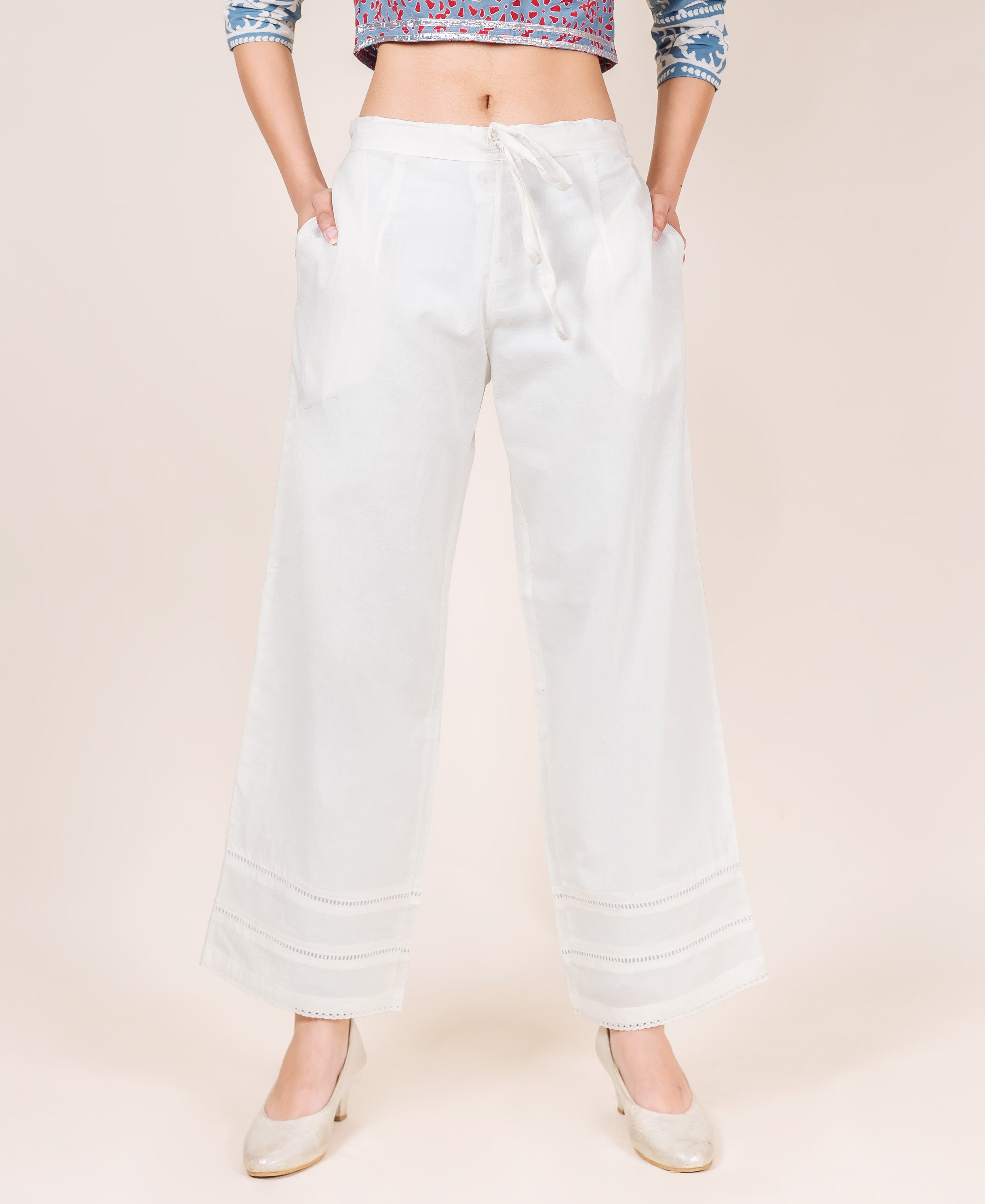 Model wearing white solid palazzo pants with a drawstring waist and lacy detailed hem.