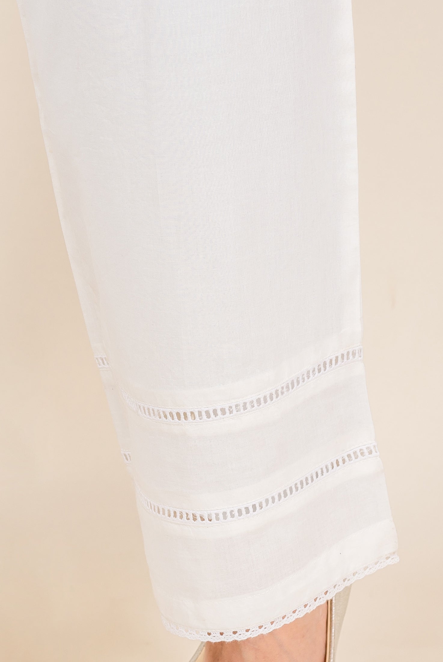 White palazzo pants with multiple horizontal eyelet lace bands and a delicate lace hem.