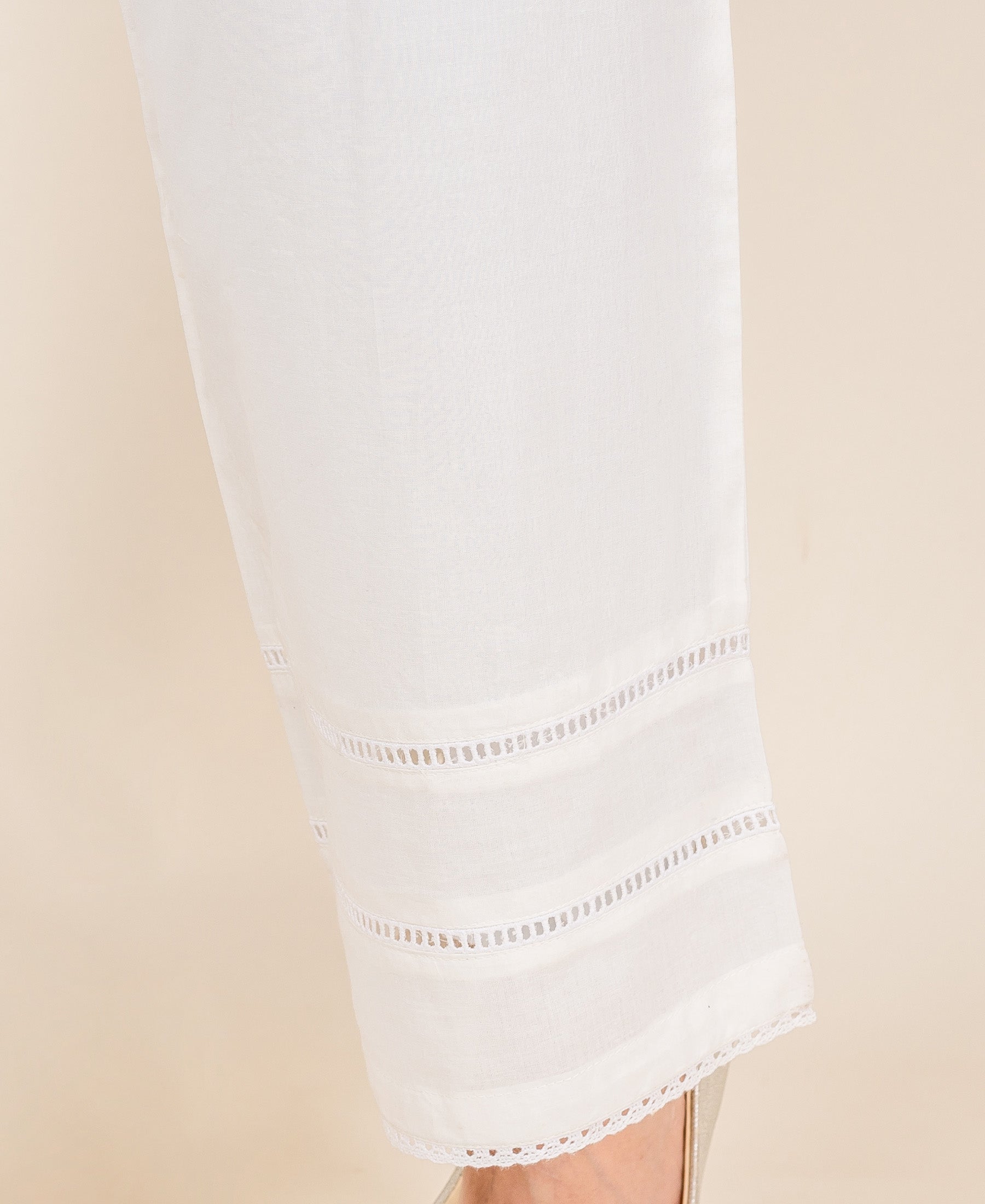 White palazzo pants with multiple horizontal eyelet lace bands and a delicate lace hem.