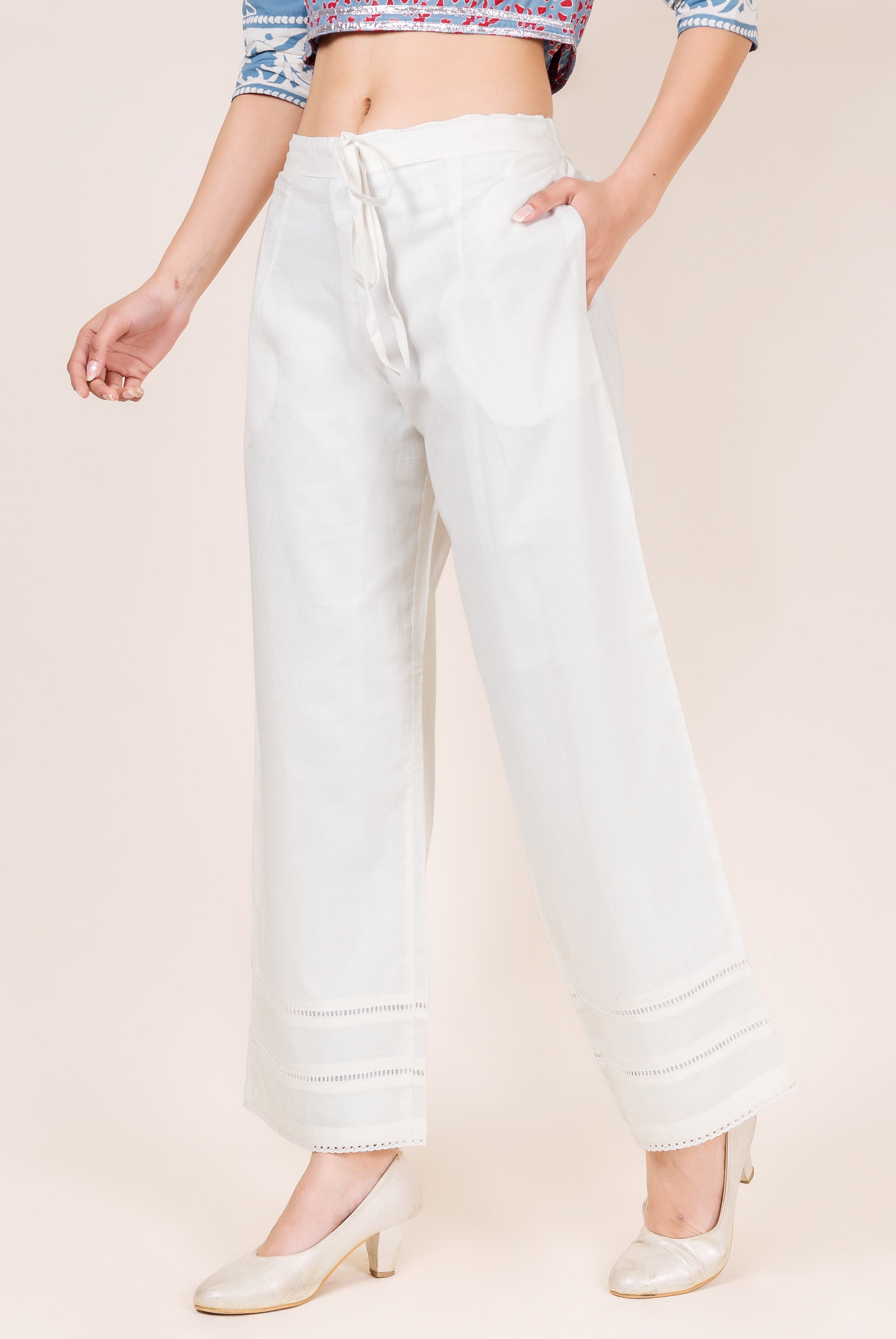 A model wearing white palazzo pants with a drawstring waist and lace trim.