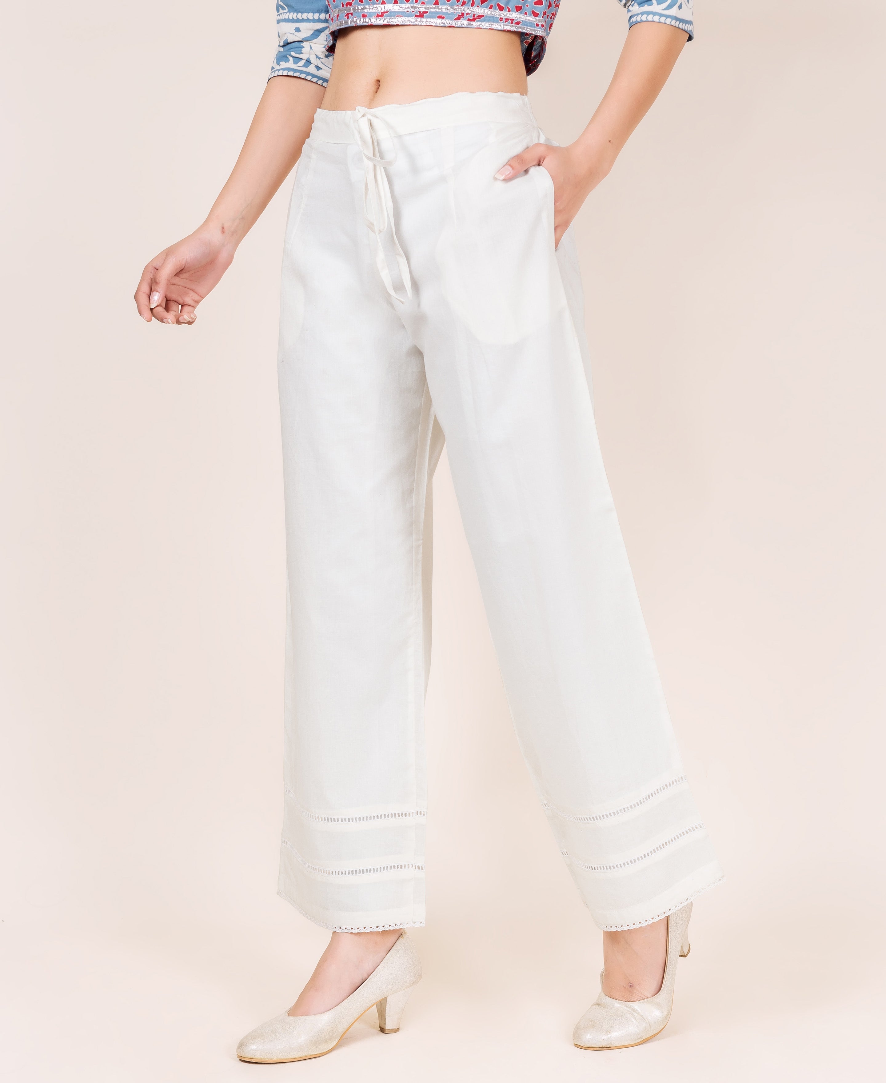 A model wearing white palazzo pants with a drawstring waist and lace trim.