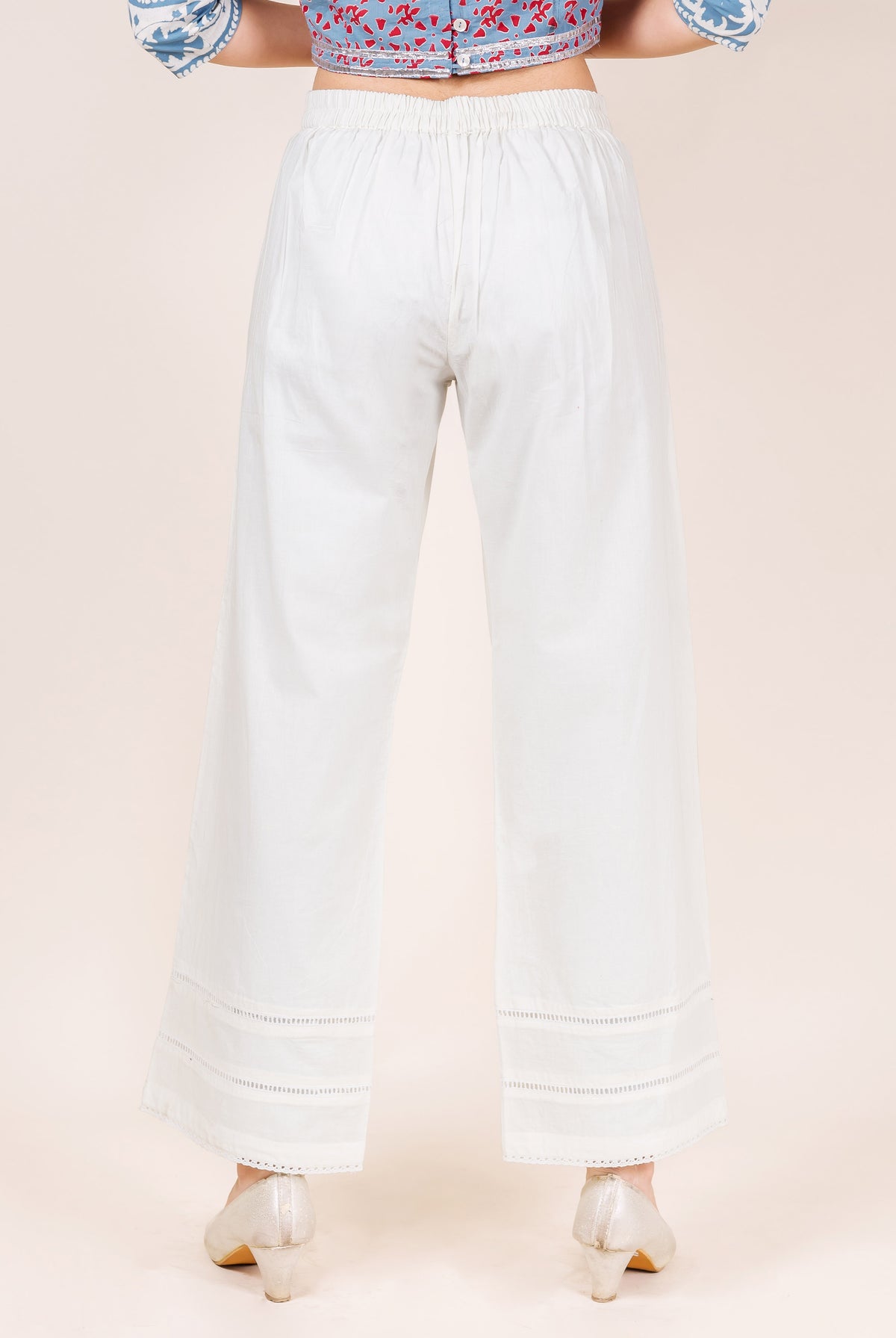 Model wearing white palazzo pants with lace trim.